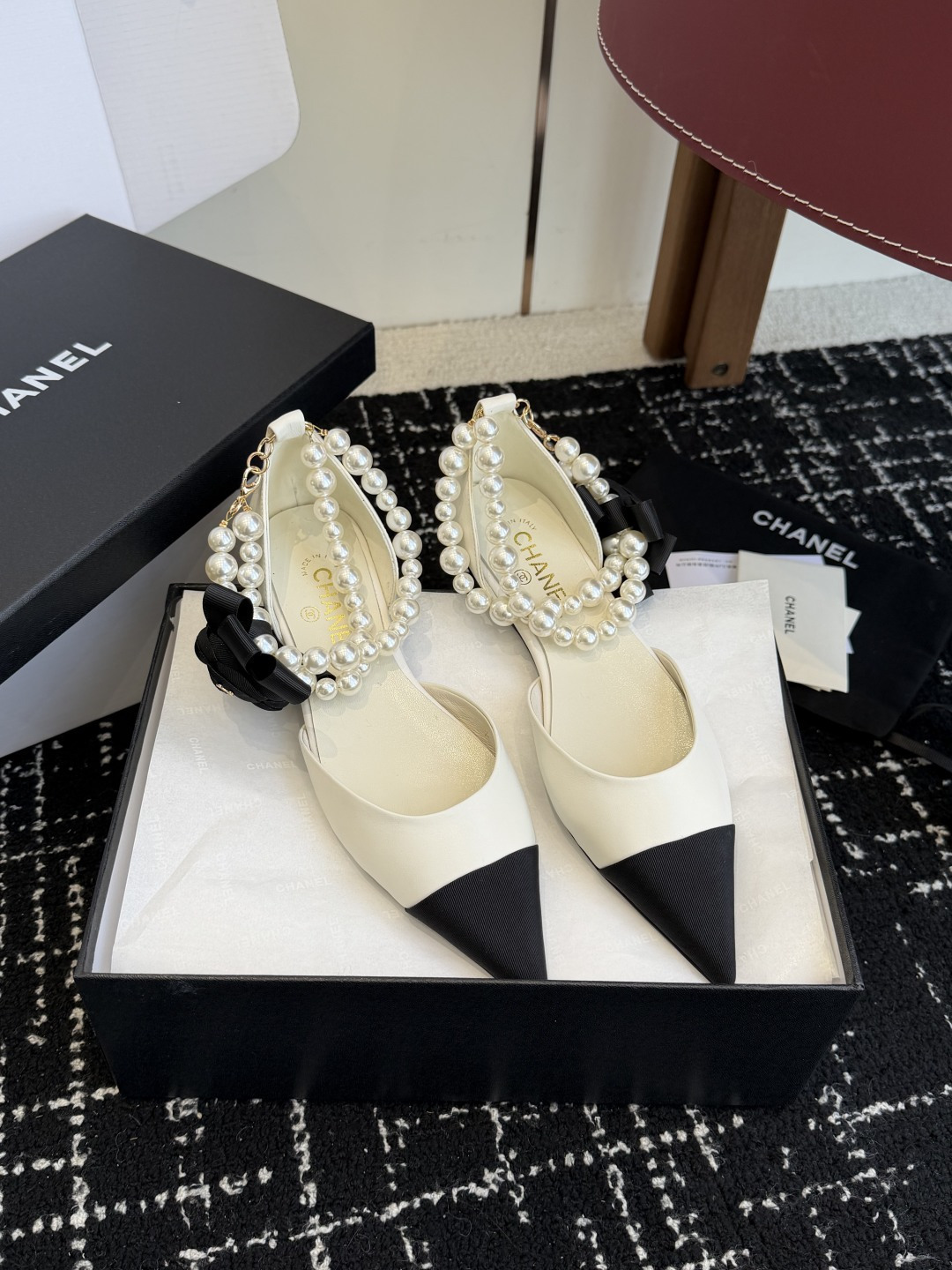 Chanel two-tone cream and black pointed-toe flats with double-strand pearl ankle straps and a black camellia flower detail. - Hình 4