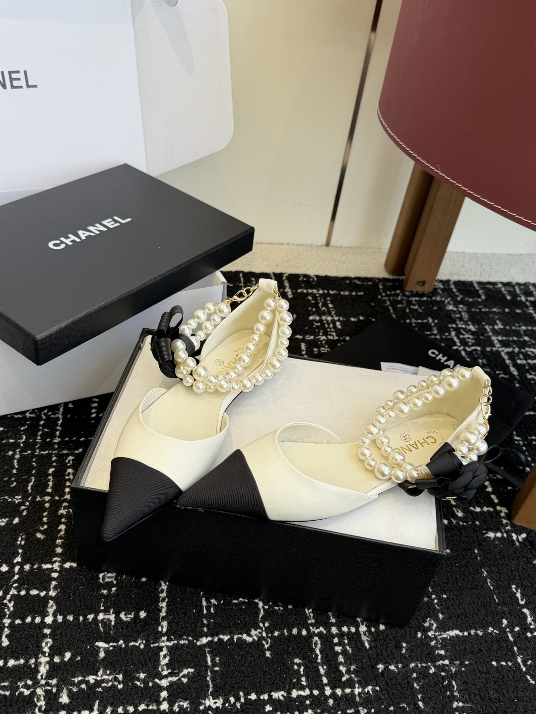 Chanel two-tone cream and black pointed-toe flats with double-strand pearl ankle straps and a black camellia flower detail. - Hình 3