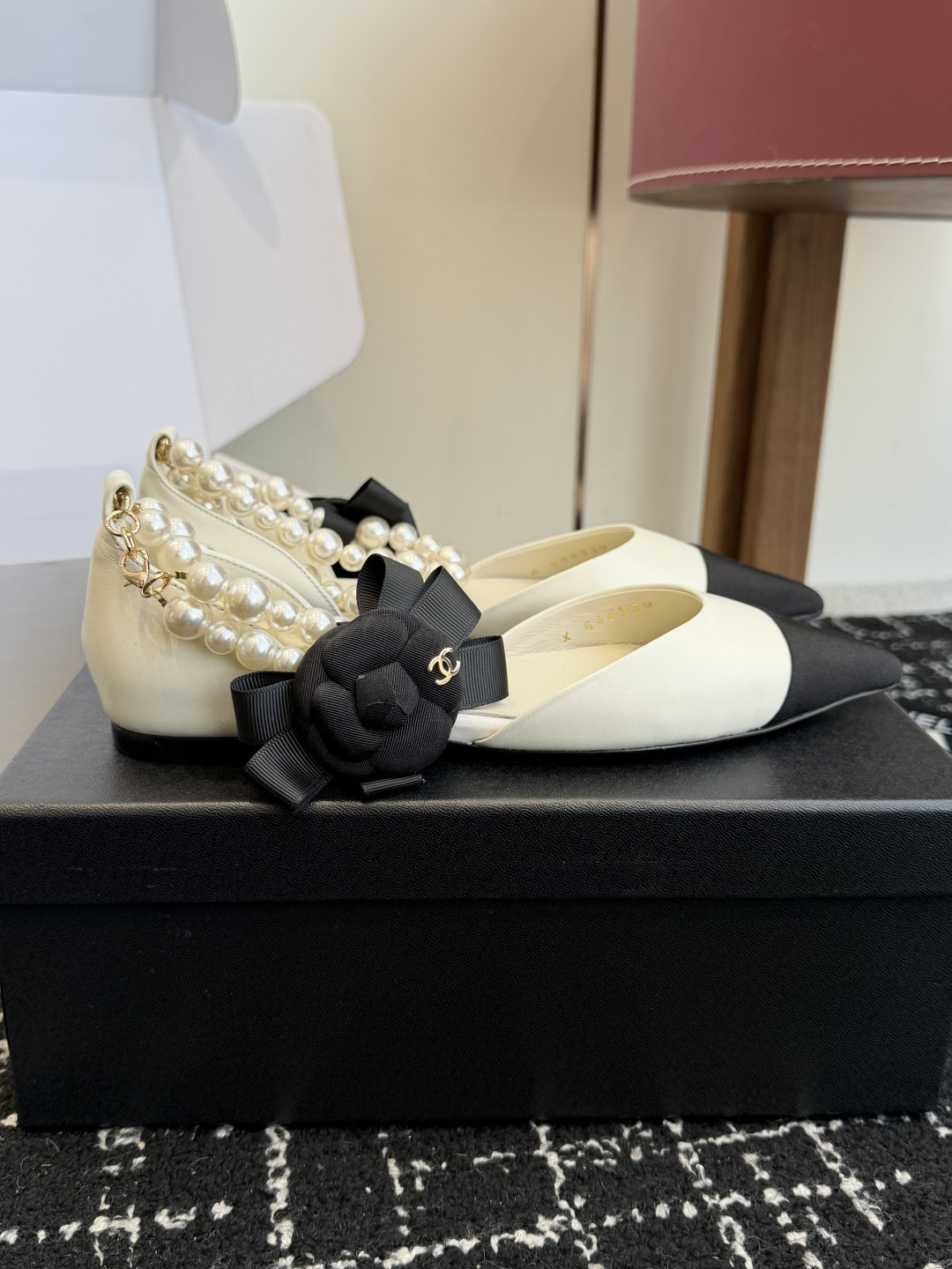 Chanel two-tone cream and black pointed-toe flats with double-strand pearl ankle straps and a black camellia flower detail. - Hình 2