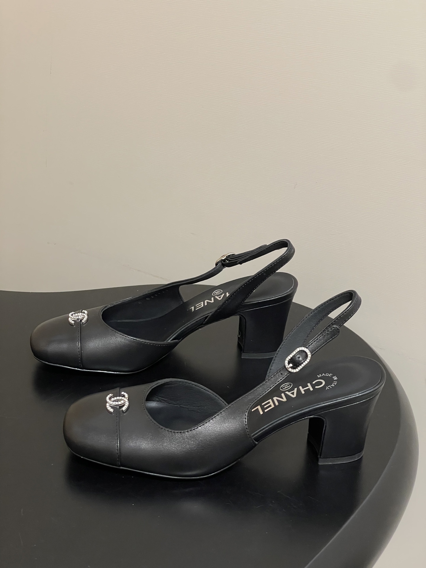 A pair of luxury black leather Chanel slingback pumps with crystal CC logos on the toes and block heels. - Hình 3
