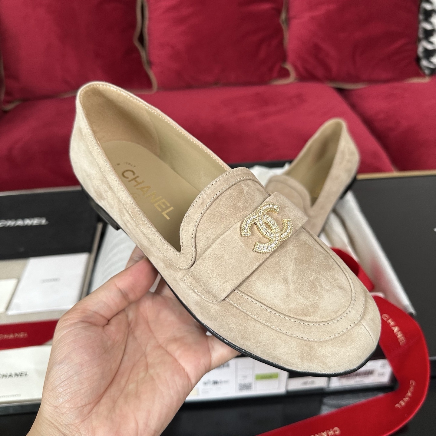 Luxury Chanel beige suede loafers featuring a gold crystal-encrusted CC logo, displayed with original black box and red ribbons. - Hình 4