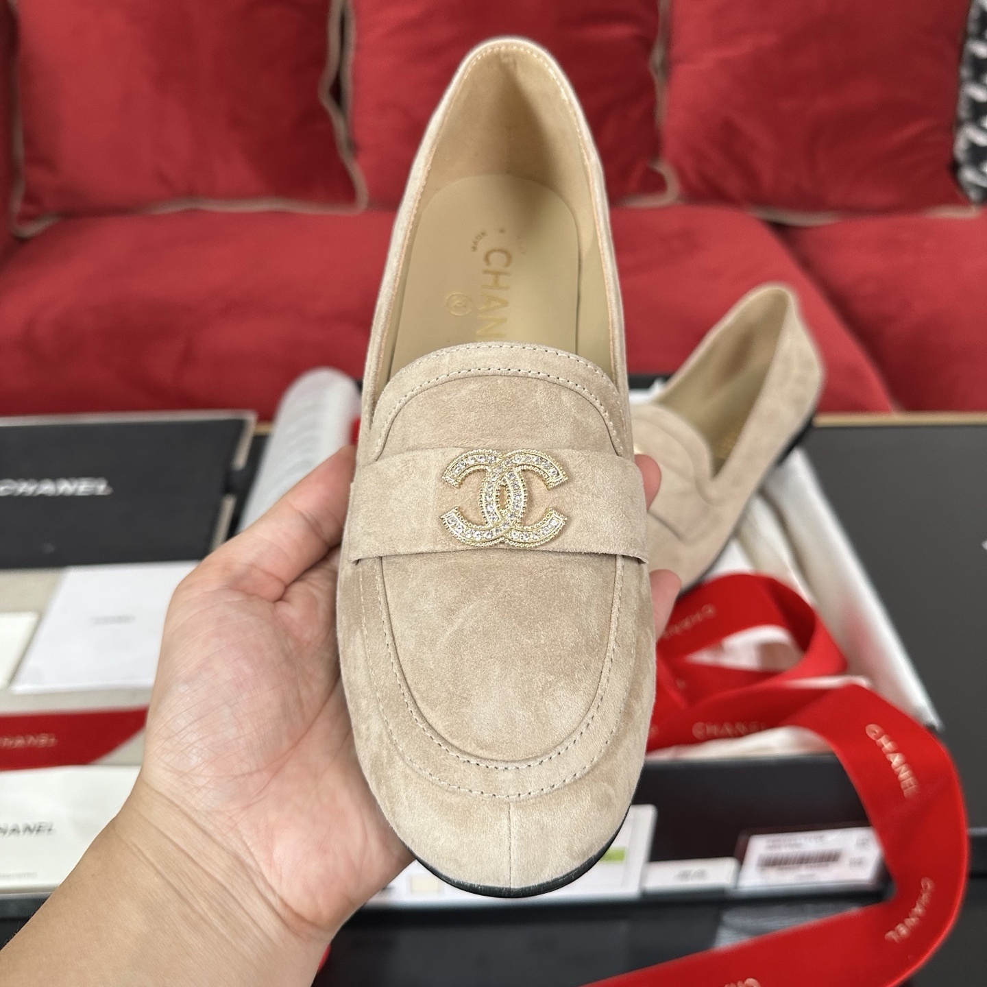 Luxury Chanel beige suede loafers featuring a gold crystal-encrusted CC logo, displayed with original black box and red ribbons. - Hình 3