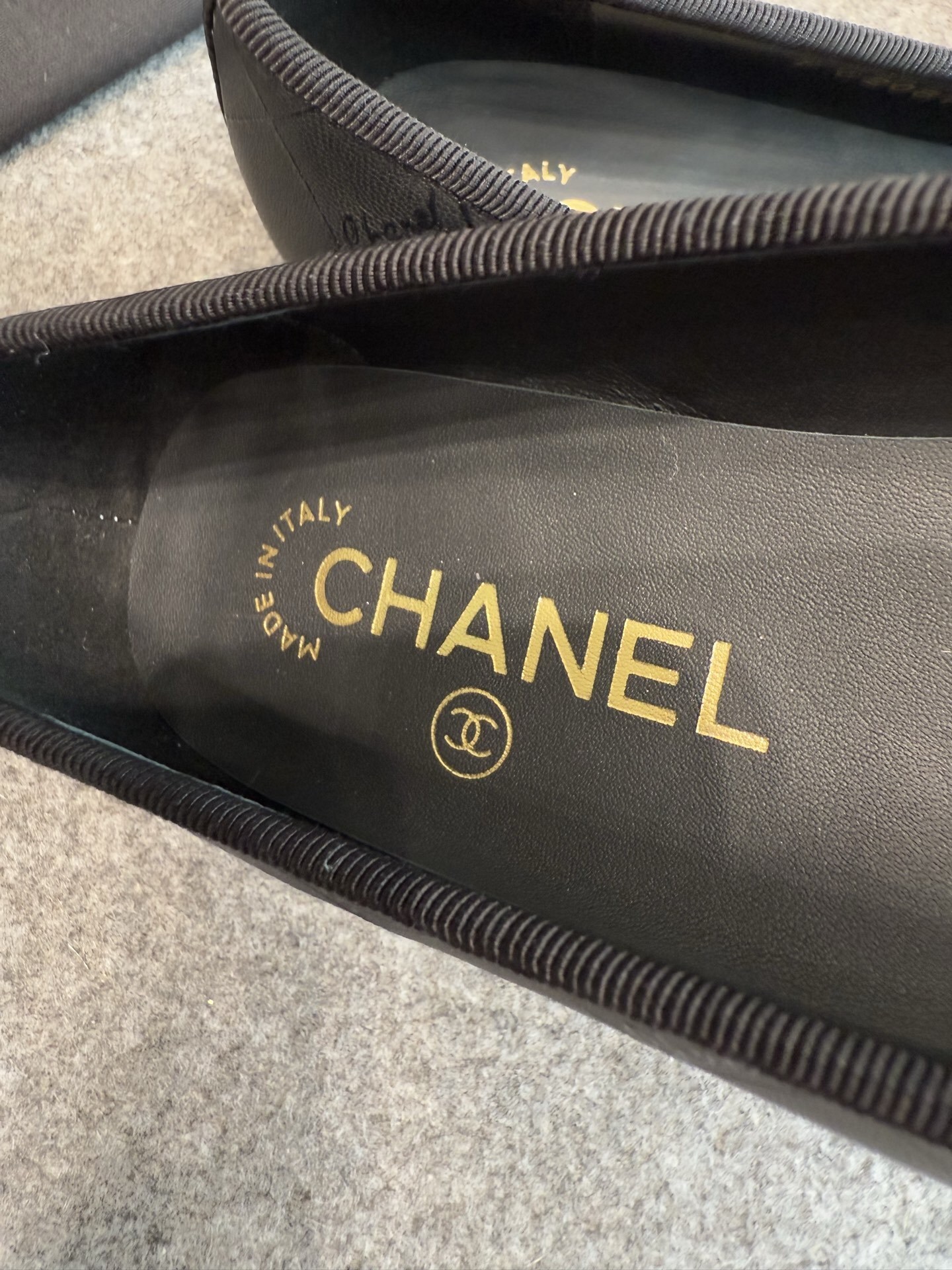 A pair of black Chanel quilted lambskin ballerina flats with patent leather CC toe caps and front bows, displayed with original luxury packaging. - Hình 8