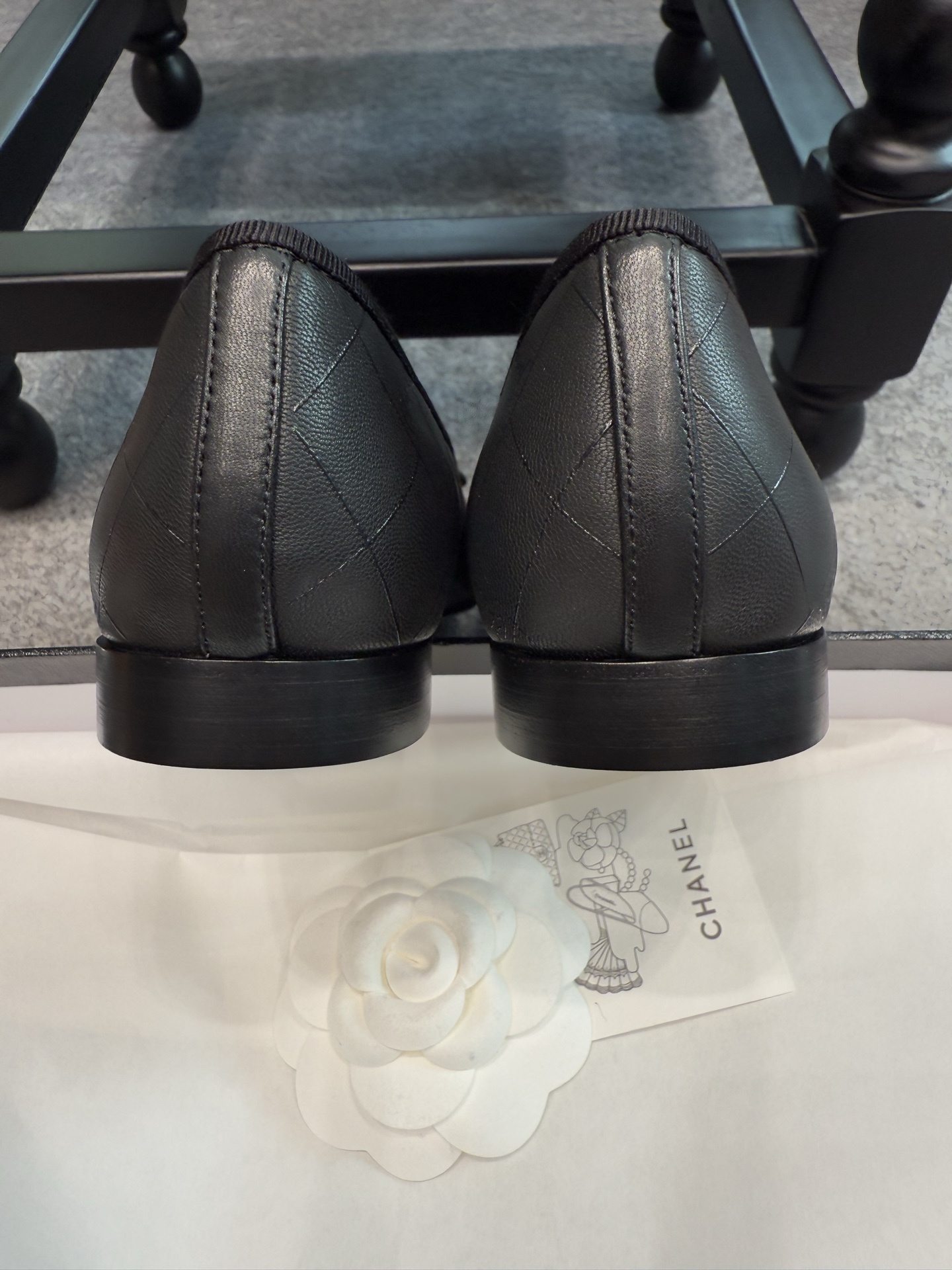 A pair of black Chanel quilted lambskin ballerina flats with patent leather CC toe caps and front bows, displayed with original luxury packaging. - Hình 2