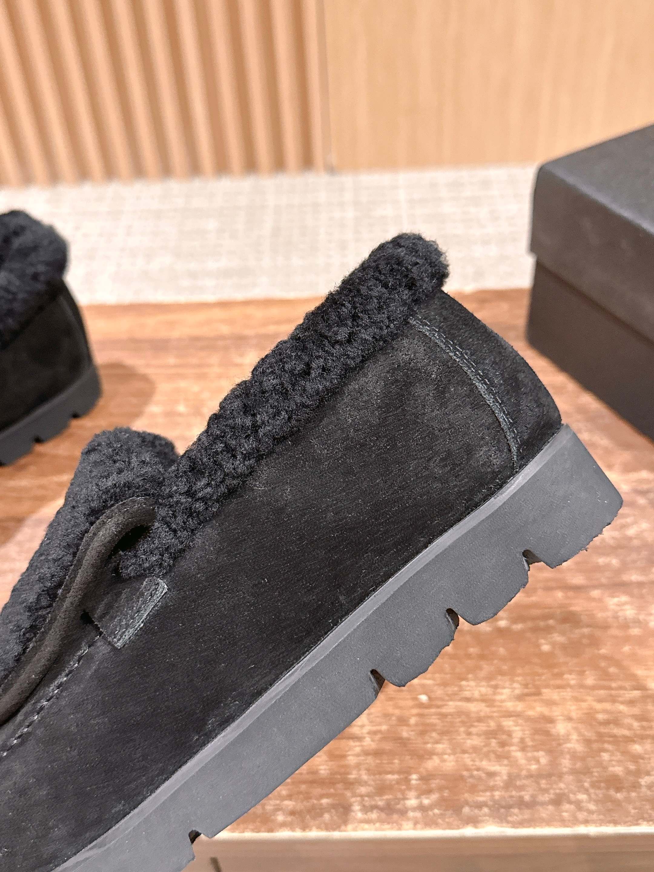 Pair of black suede loafers with thick shearling lining and a gold interlocking logo on the front sitting on a wooden surface. - Hình 7