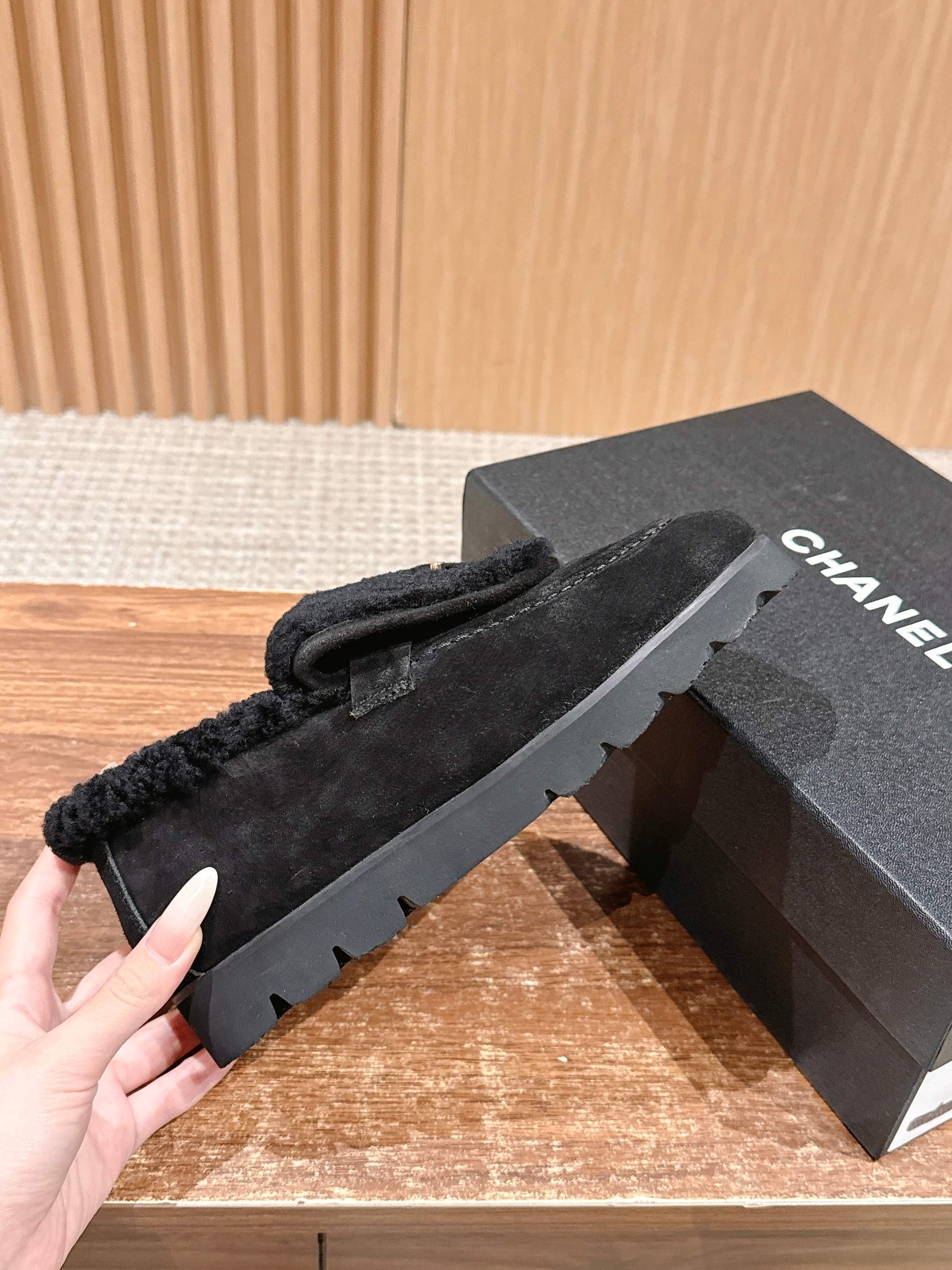 Pair of black suede loafers with thick shearling lining and a gold interlocking logo on the front sitting on a wooden surface. - Hình 5