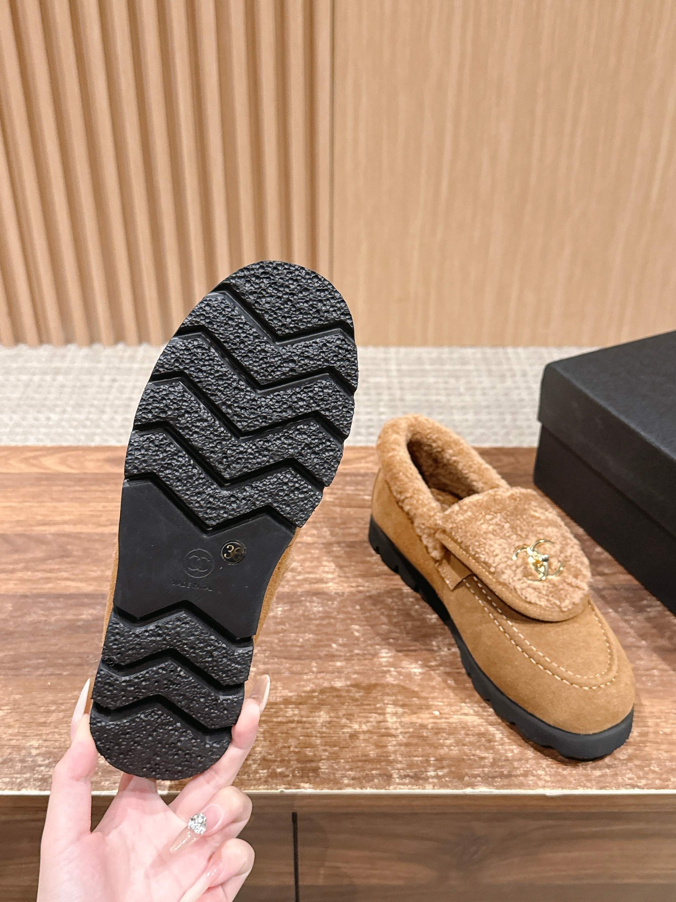 Pair of brown suede loafers with thick shearling lining and gold interlocking logo on a wooden surface - Hình 9