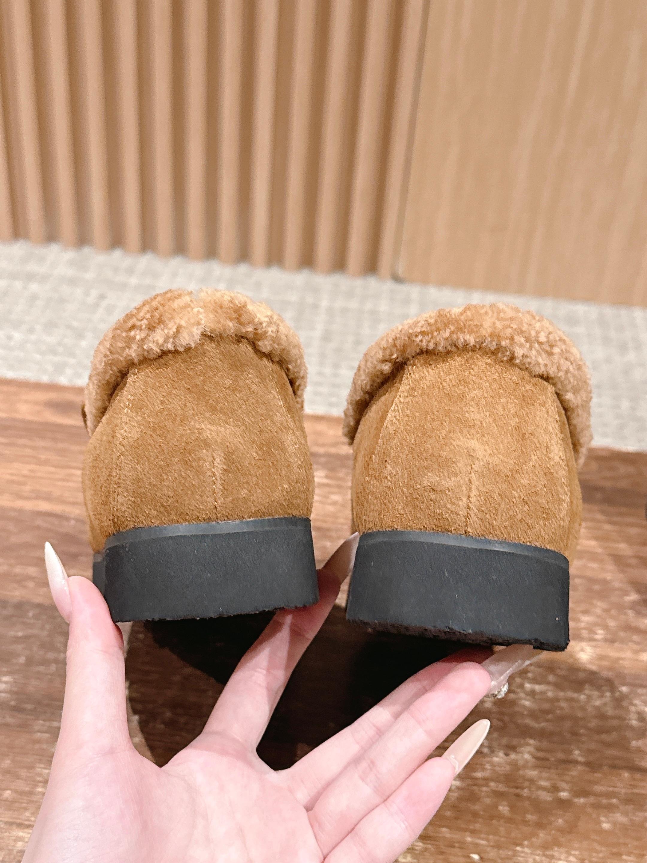 Pair of brown suede loafers with thick shearling lining and gold interlocking logo on a wooden surface - Hình 8