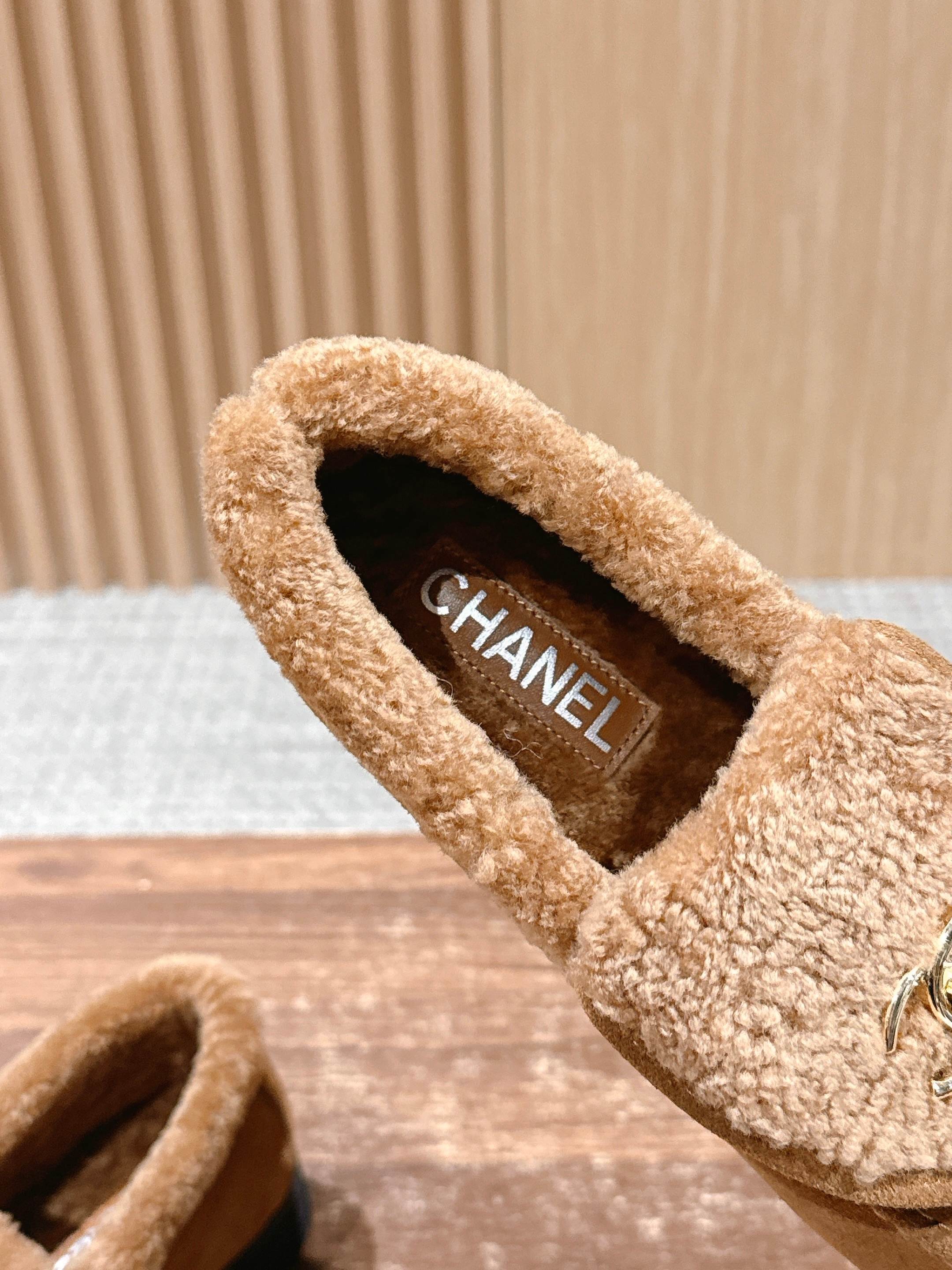 Pair of brown suede loafers with thick shearling lining and gold interlocking logo on a wooden surface - Hình 7