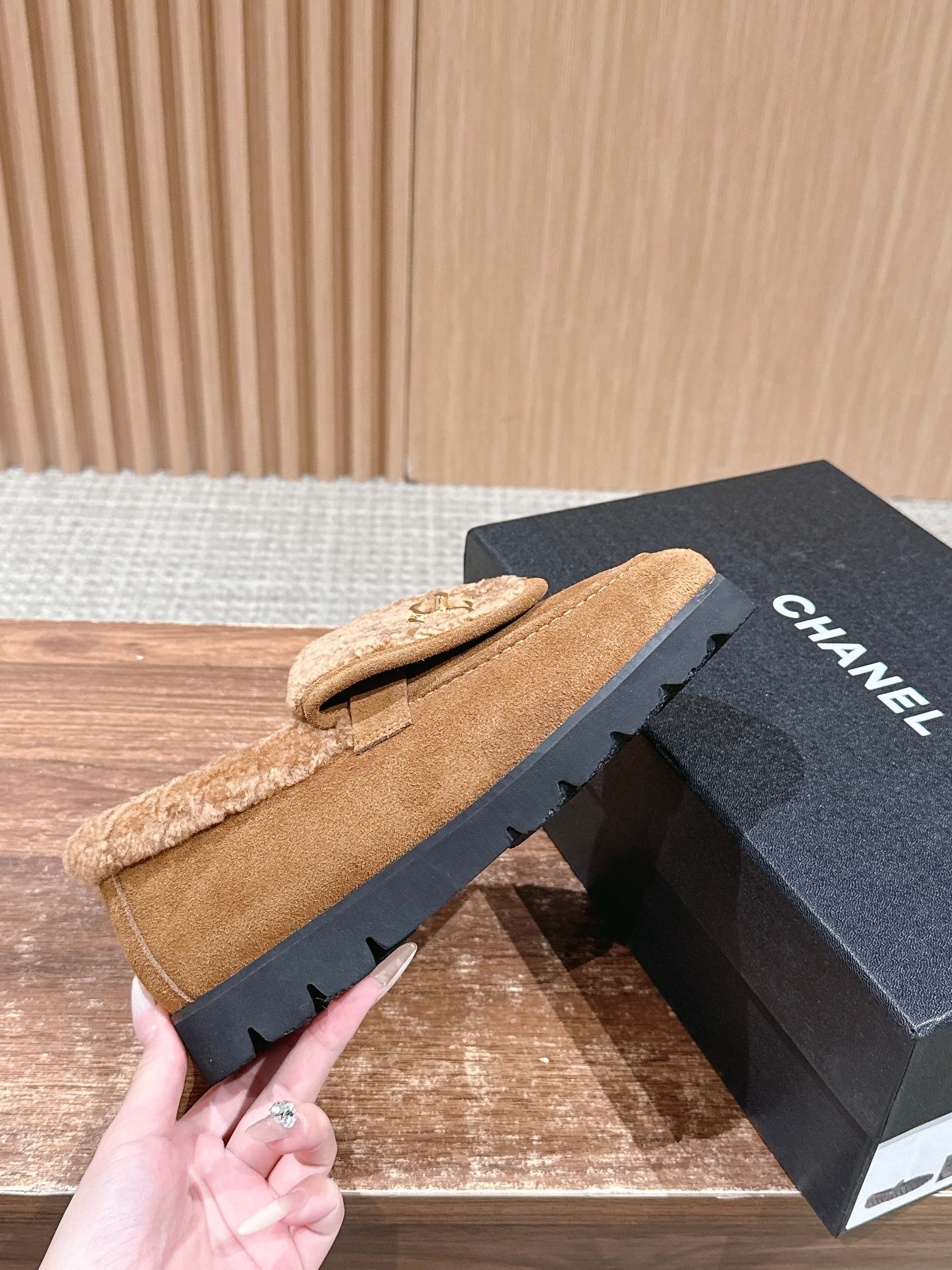 Pair of brown suede loafers with thick shearling lining and gold interlocking logo on a wooden surface - Hình 5