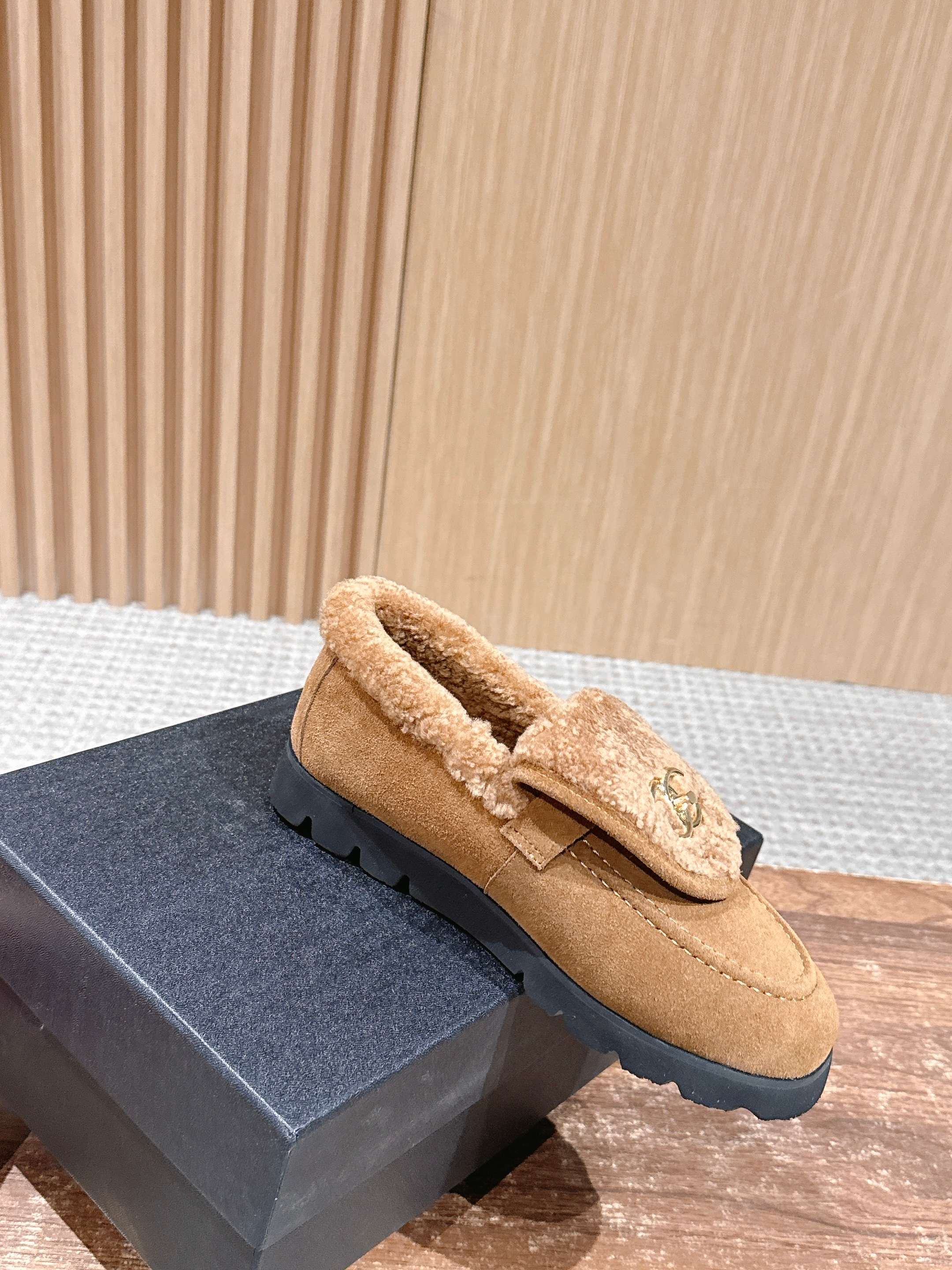 Pair of brown suede loafers with thick shearling lining and gold interlocking logo on a wooden surface - Hình 3