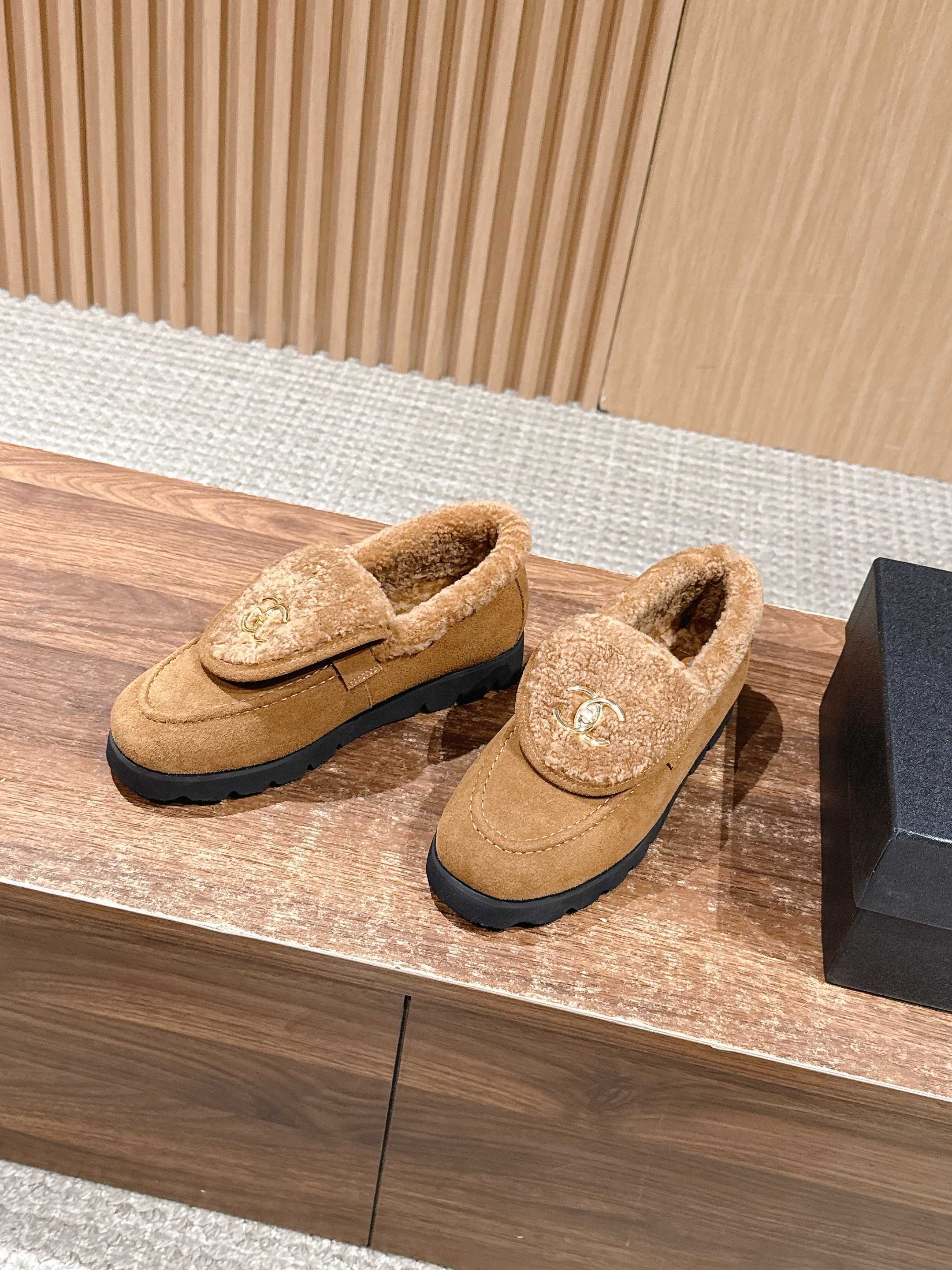 Pair of brown suede loafers with thick shearling lining and gold interlocking logo on a wooden surface - Hình 2