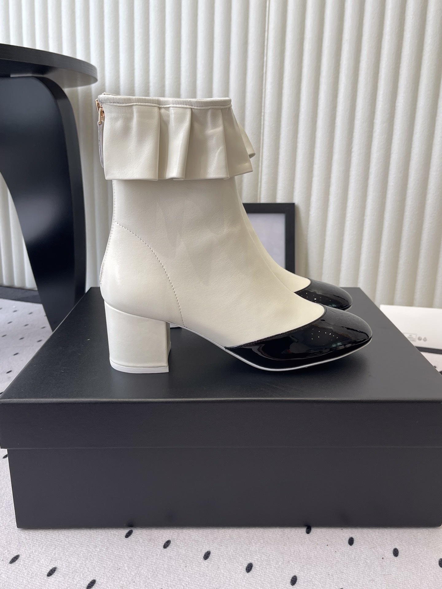 Chanel two-tone white and black leather ankle boots with ruffle collar and block heel on a black box. - Hình 2