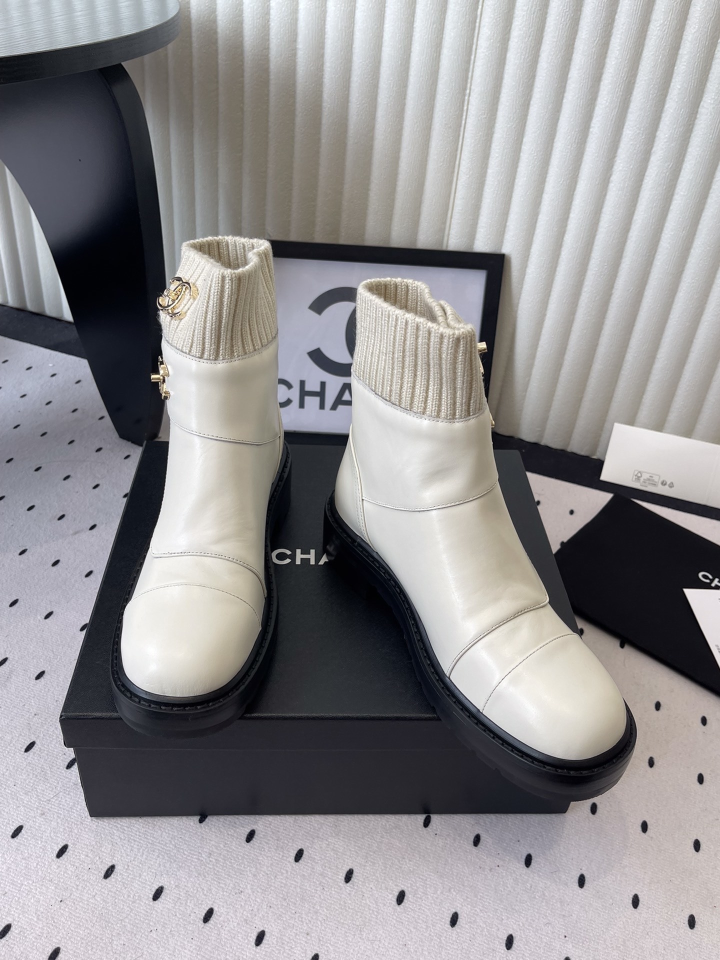 Pair of Chanel off-white leather ankle boots with ribbed knit collars and gold CC logos displayed on a black box. - Hình 7