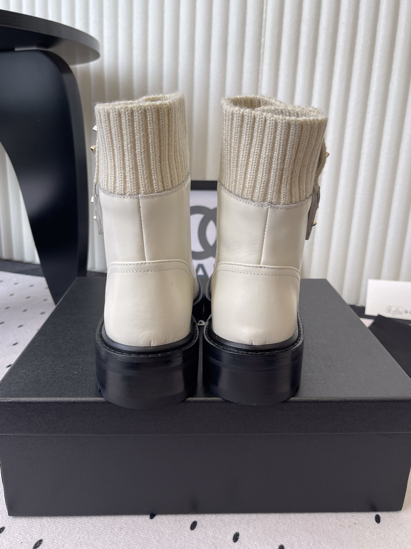 Pair of Chanel off-white leather ankle boots with ribbed knit collars and gold CC logos displayed on a black box. - Hình 3