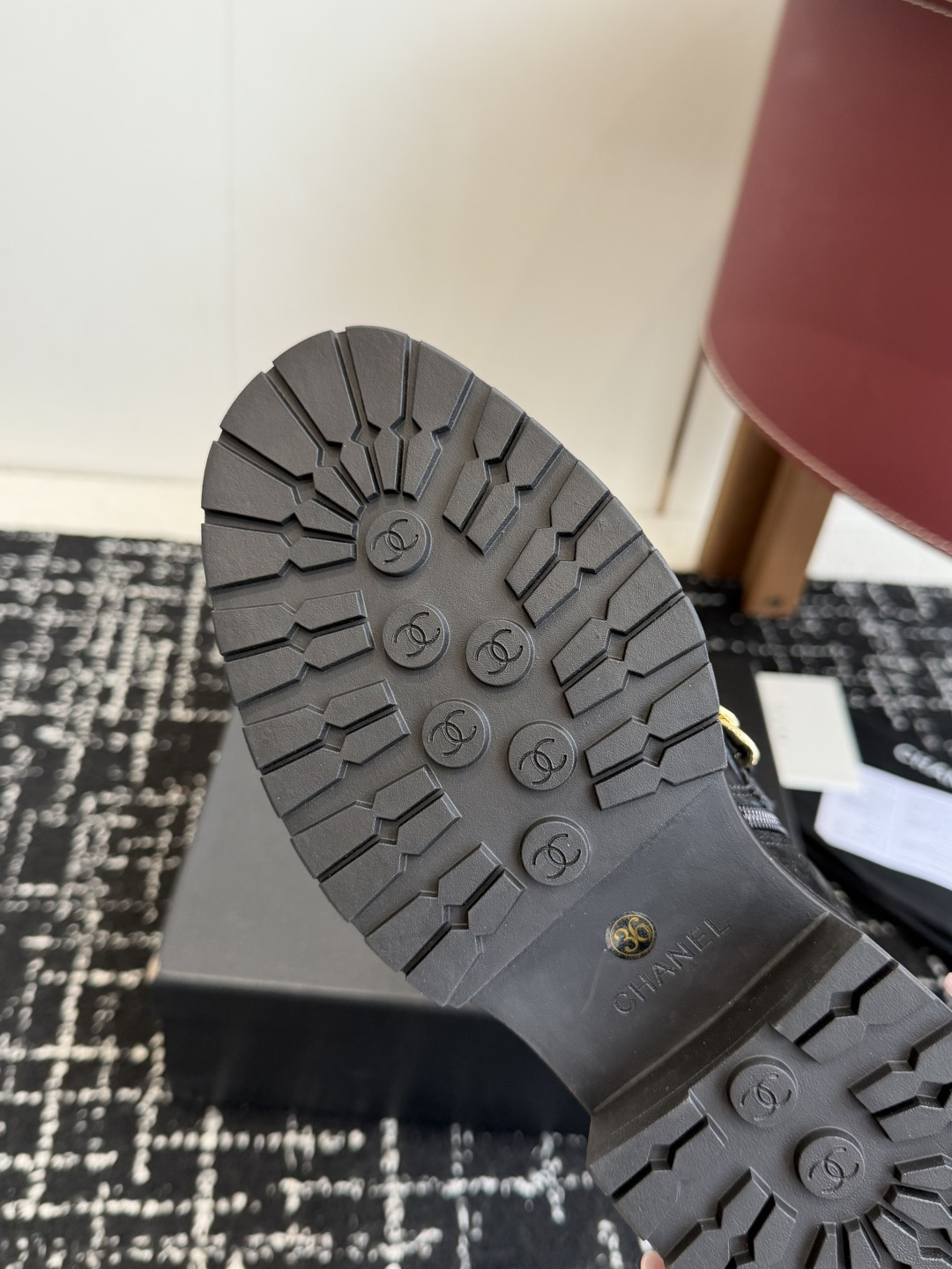 Pair of black Chanel quilted suede ankle boots with gold chain and patent leather toe caps on a black box - Hình 9