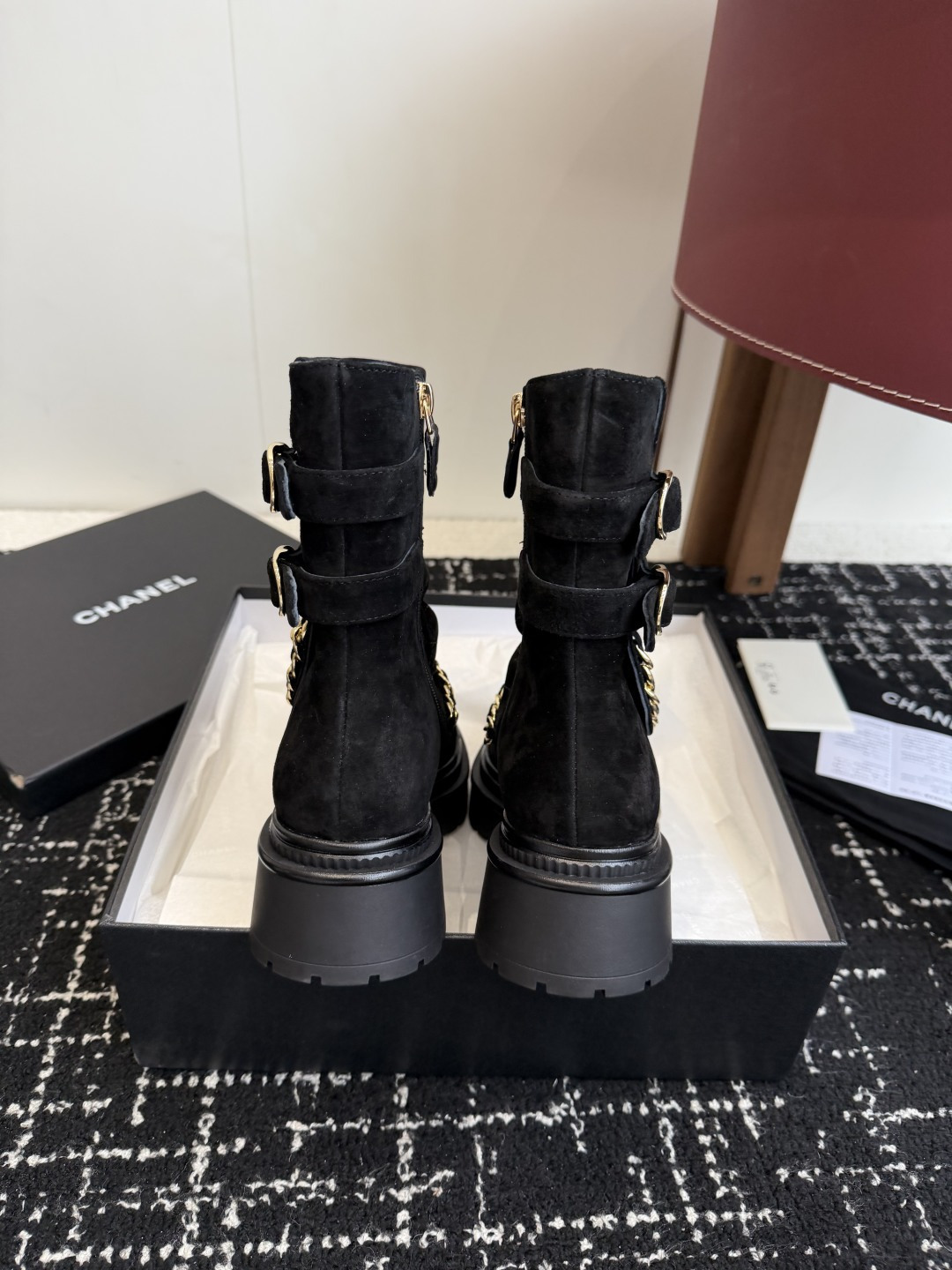 Pair of black Chanel quilted suede ankle boots with gold chain and patent leather toe caps on a black box - Hình 8