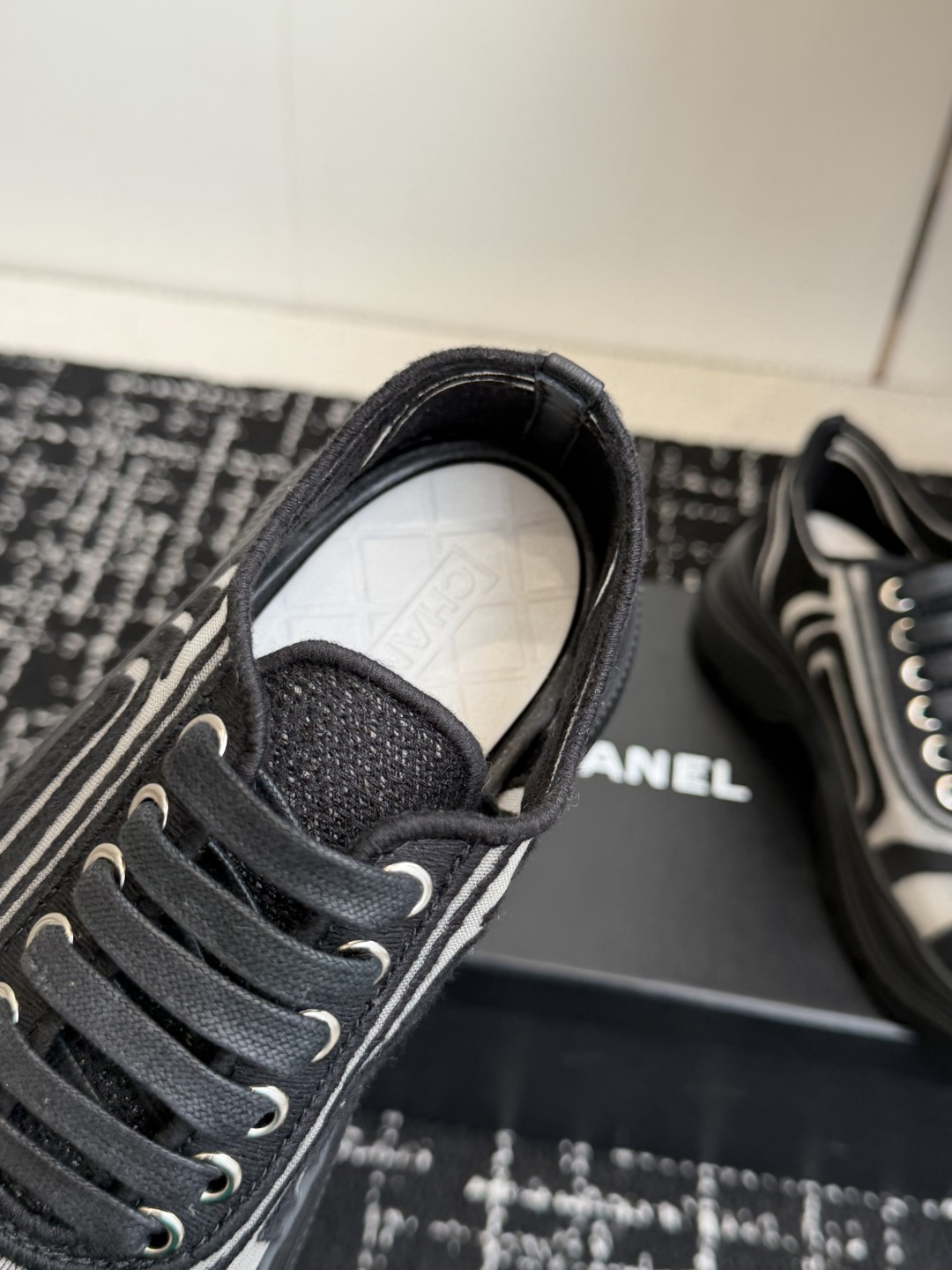 Pair of black and white Chanel mesh sneakers with wavy patterns and CC logo on a black box - Hình 7