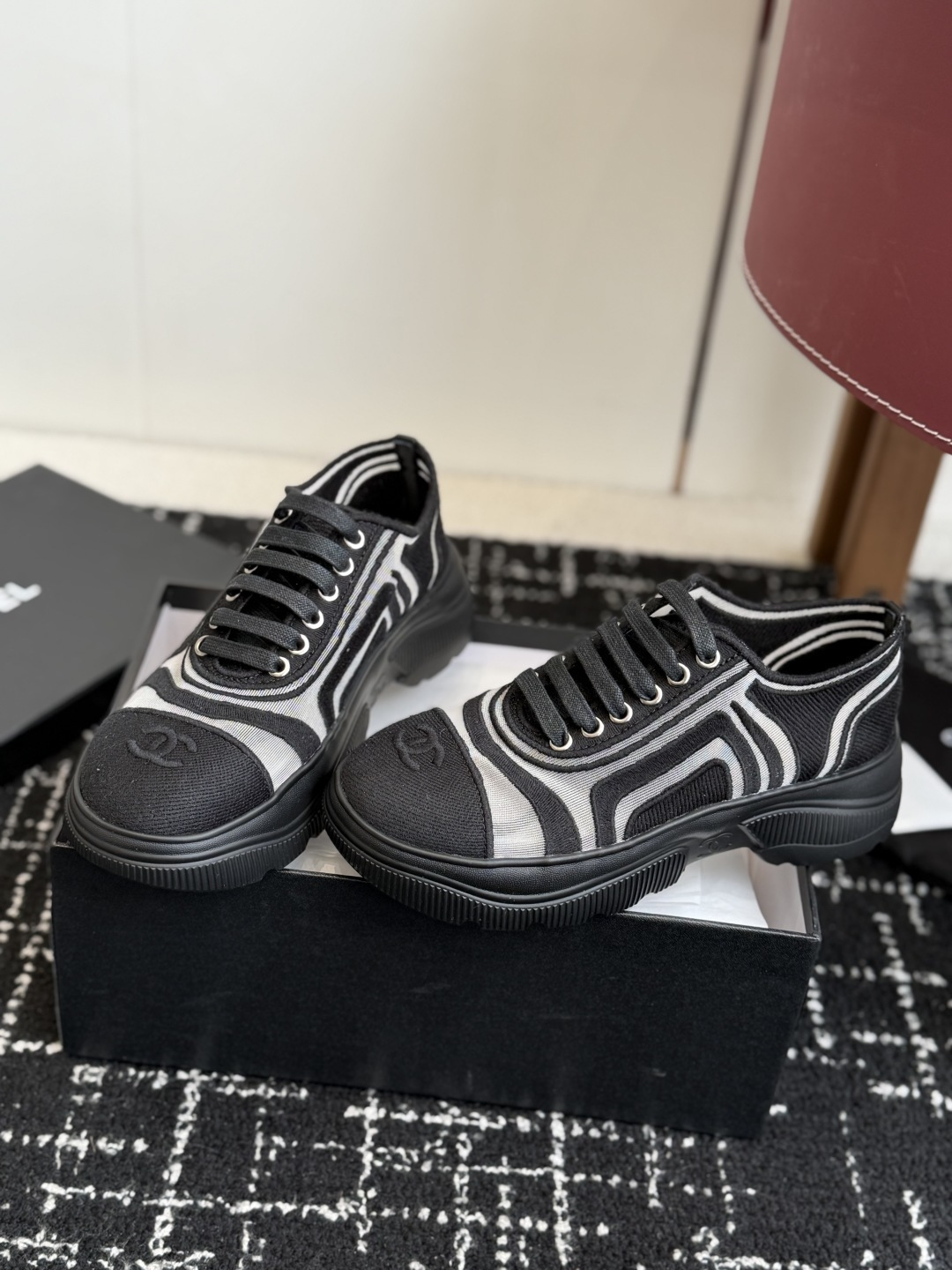 Pair of black and white Chanel mesh sneakers with wavy patterns and CC logo on a black box - Hình 3