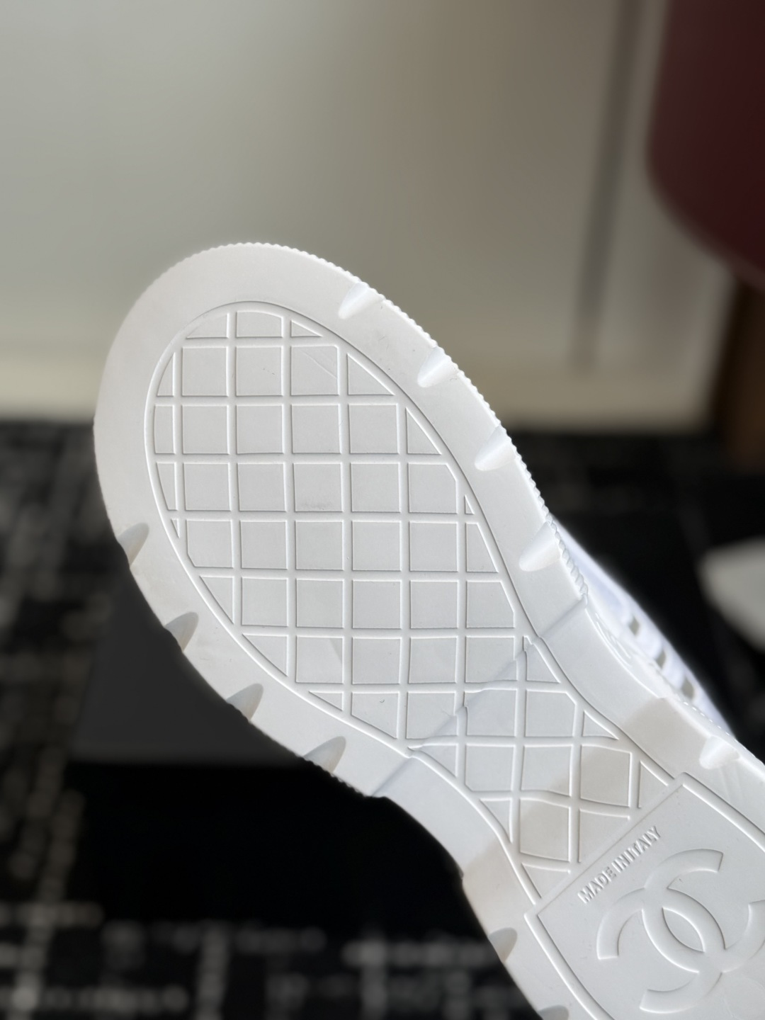 Pair of white Chanel sneakers with mesh panels and double C logo on the toe cap, placed on a black designer shoe box. - Hình 9