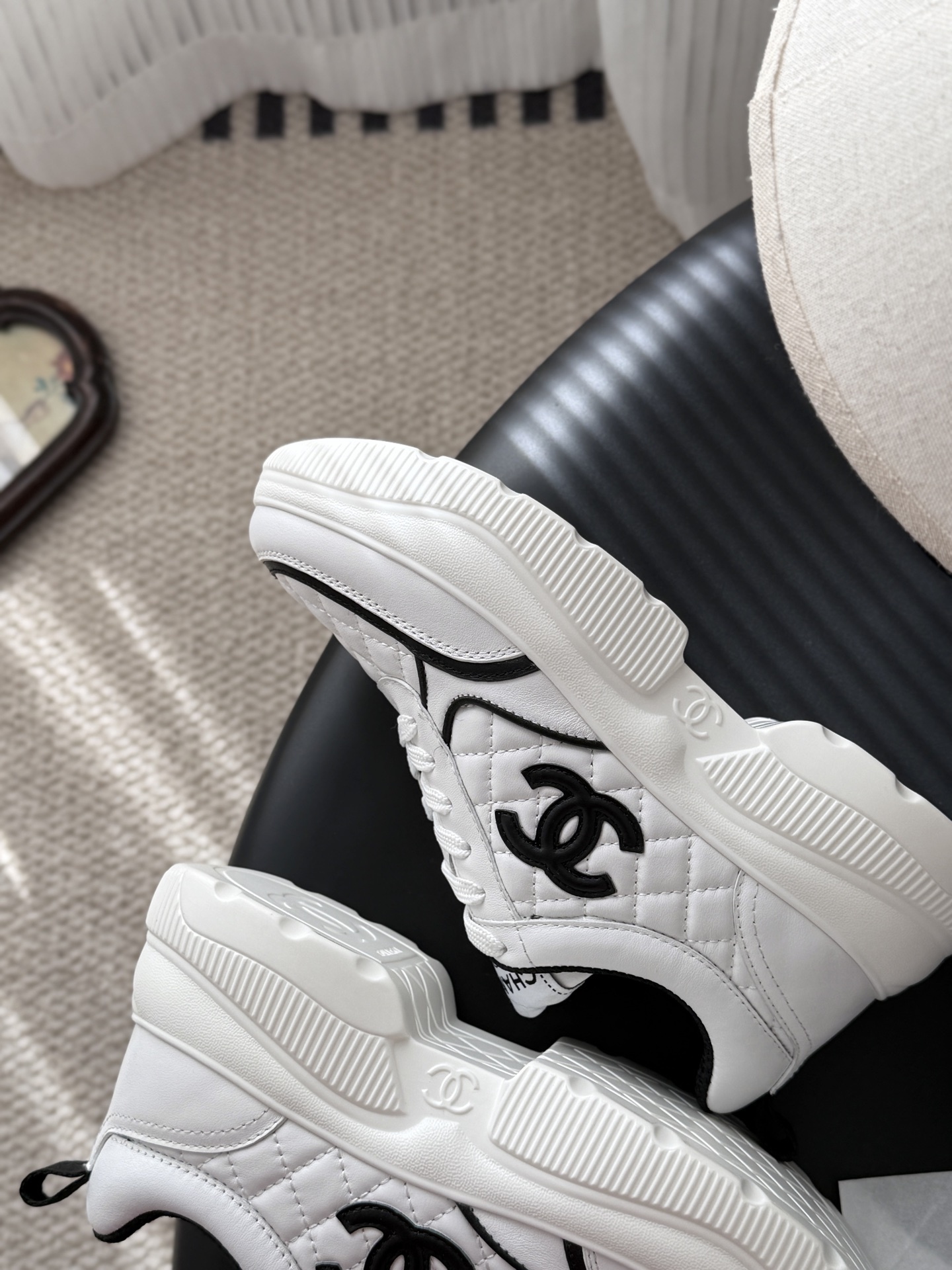A pair of white Chanel quilted leather sneakers with black CC logo and chunky white soles next to a black Chanel box - Hình 7