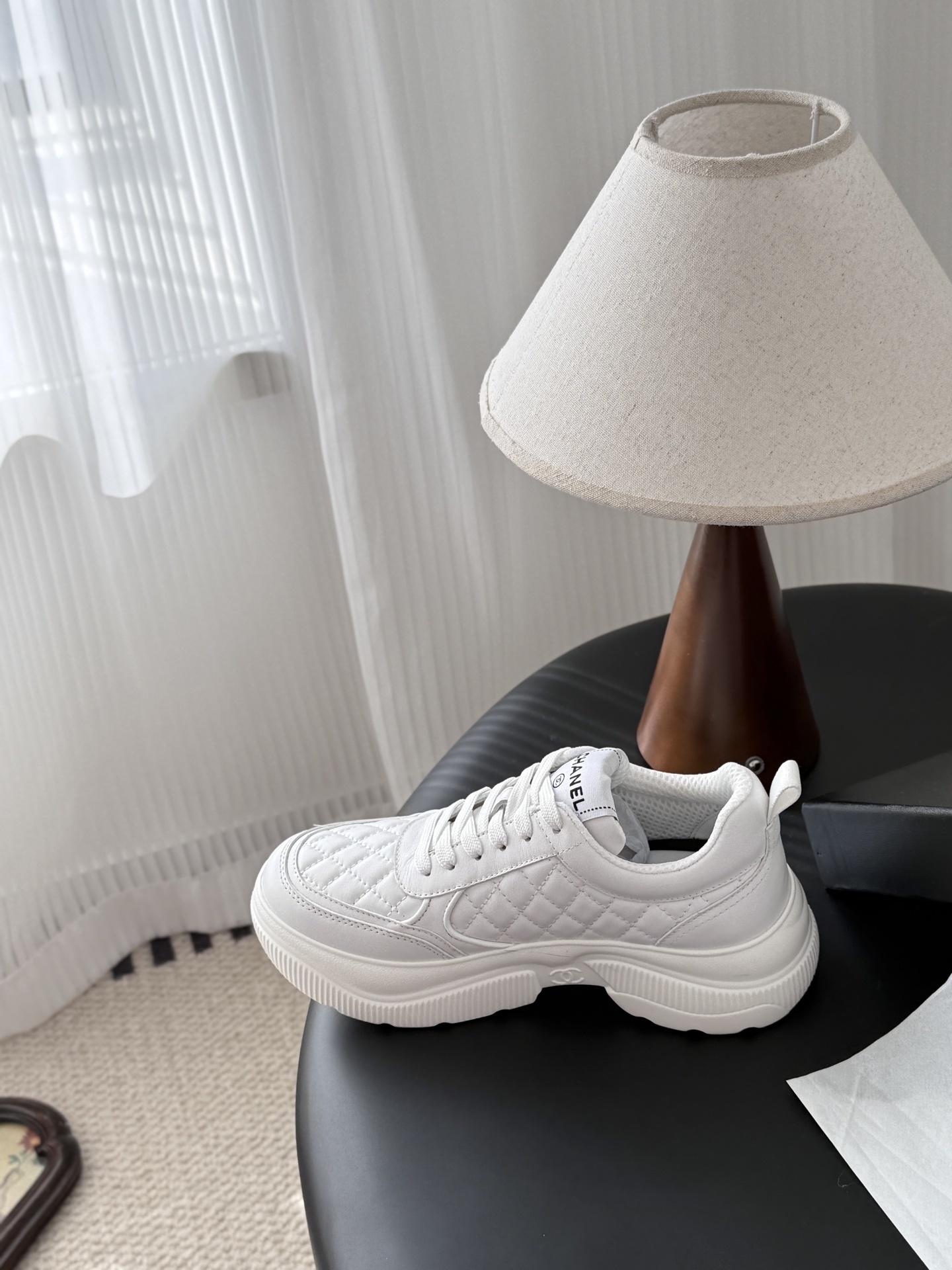 A pair of luxury Chanel white quilted leather sneakers next to their original black designer box - Hình 8