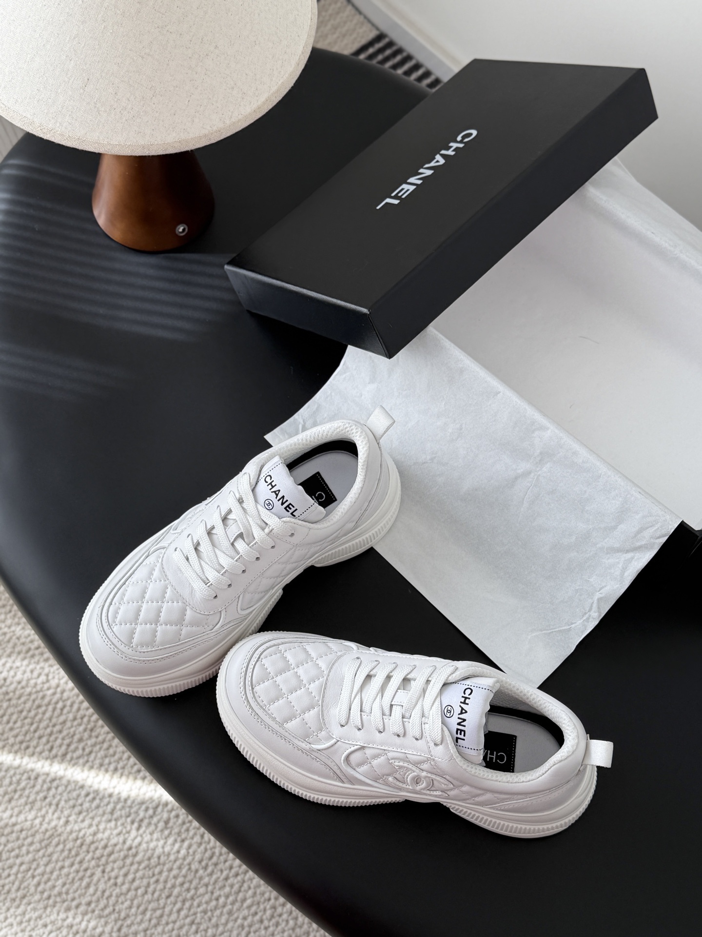 A pair of luxury Chanel white quilted leather sneakers next to their original black designer box - Hình 6
