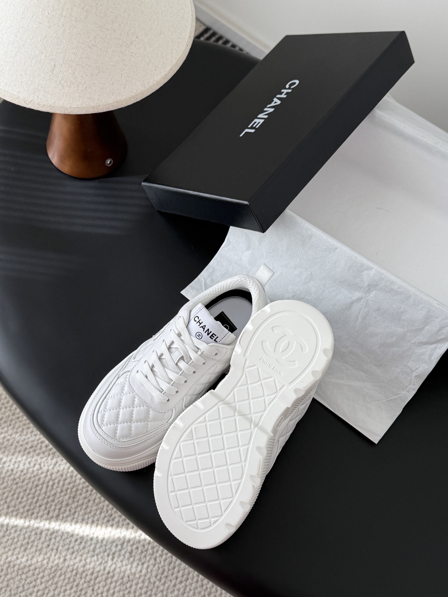 A pair of luxury Chanel white quilted leather sneakers next to their original black designer box - Hình 5