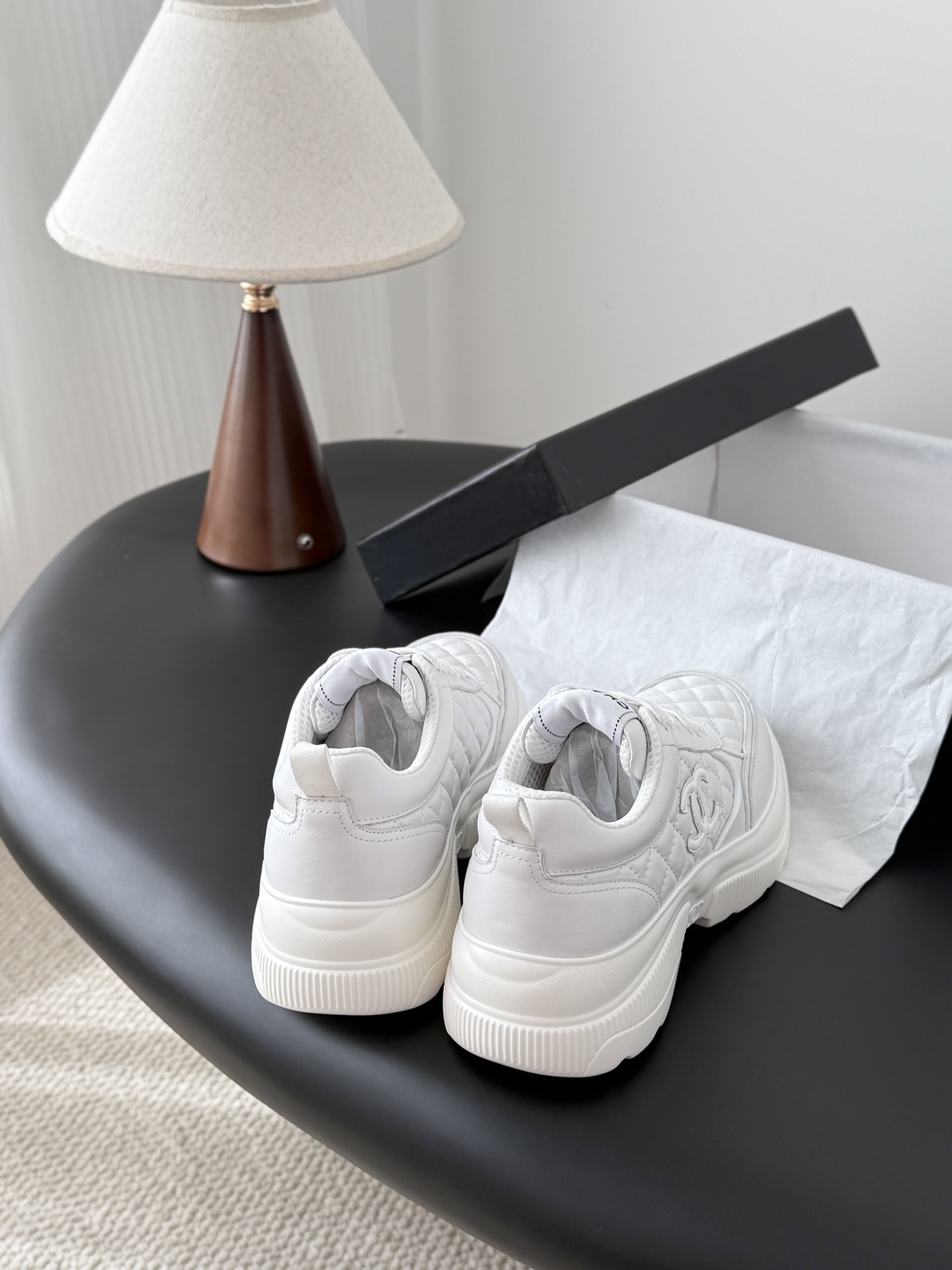 A pair of luxury Chanel white quilted leather sneakers next to their original black designer box - Hình 3