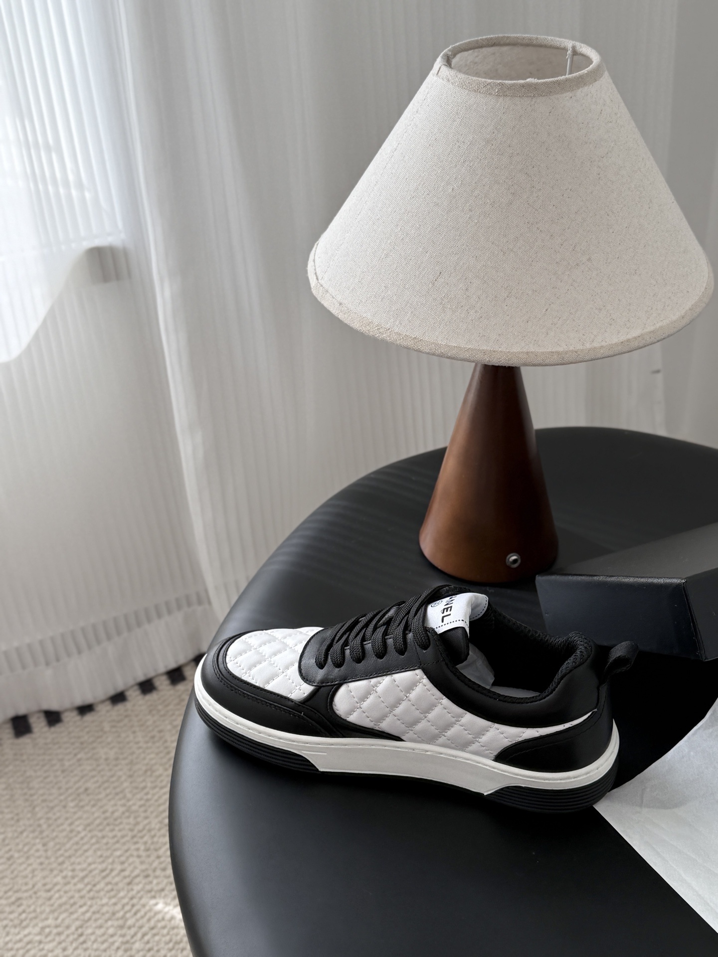 A pair of luxury Chanel black and white quilted leather sneakers with CC logo next to their original black box. - Hình 8