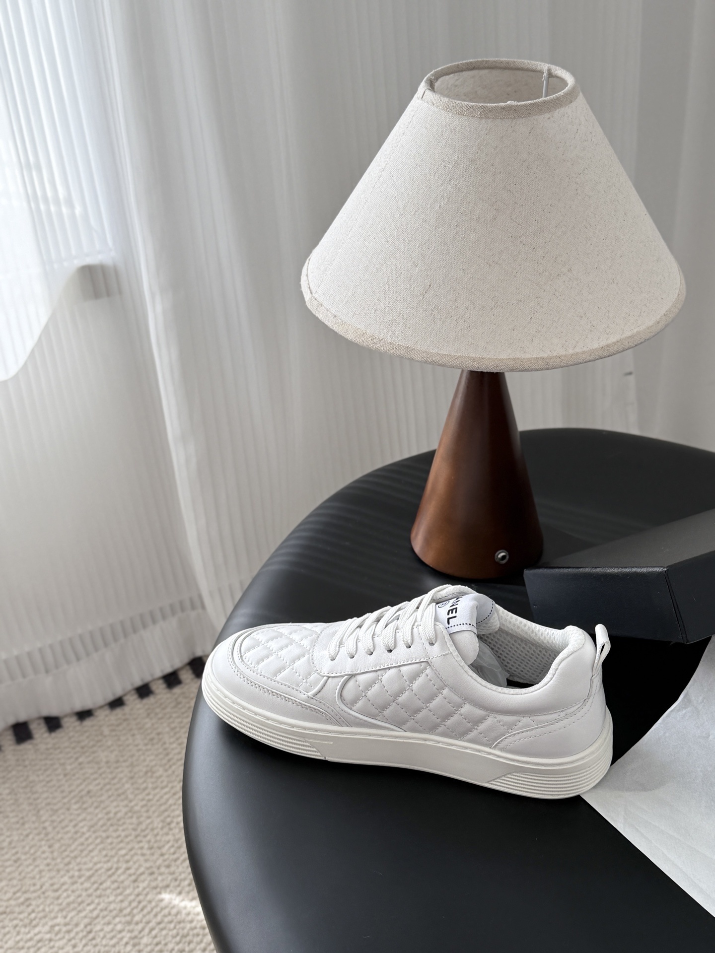 A pair of luxury Chanel white quilted leather sneakers with the CC logo next to their original black box. - Hình 8