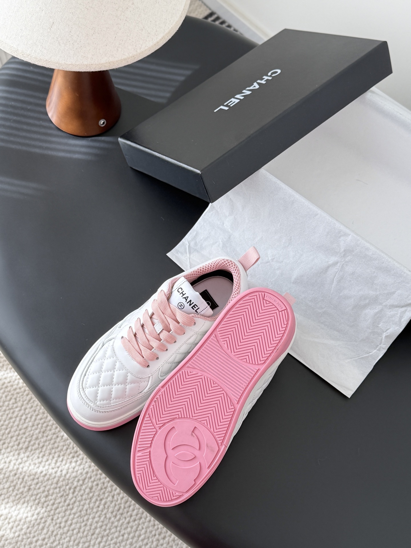 Pair of Chanel white quilted leather sneakers with pink laces and pink soles next to a black Chanel box - Hình 5