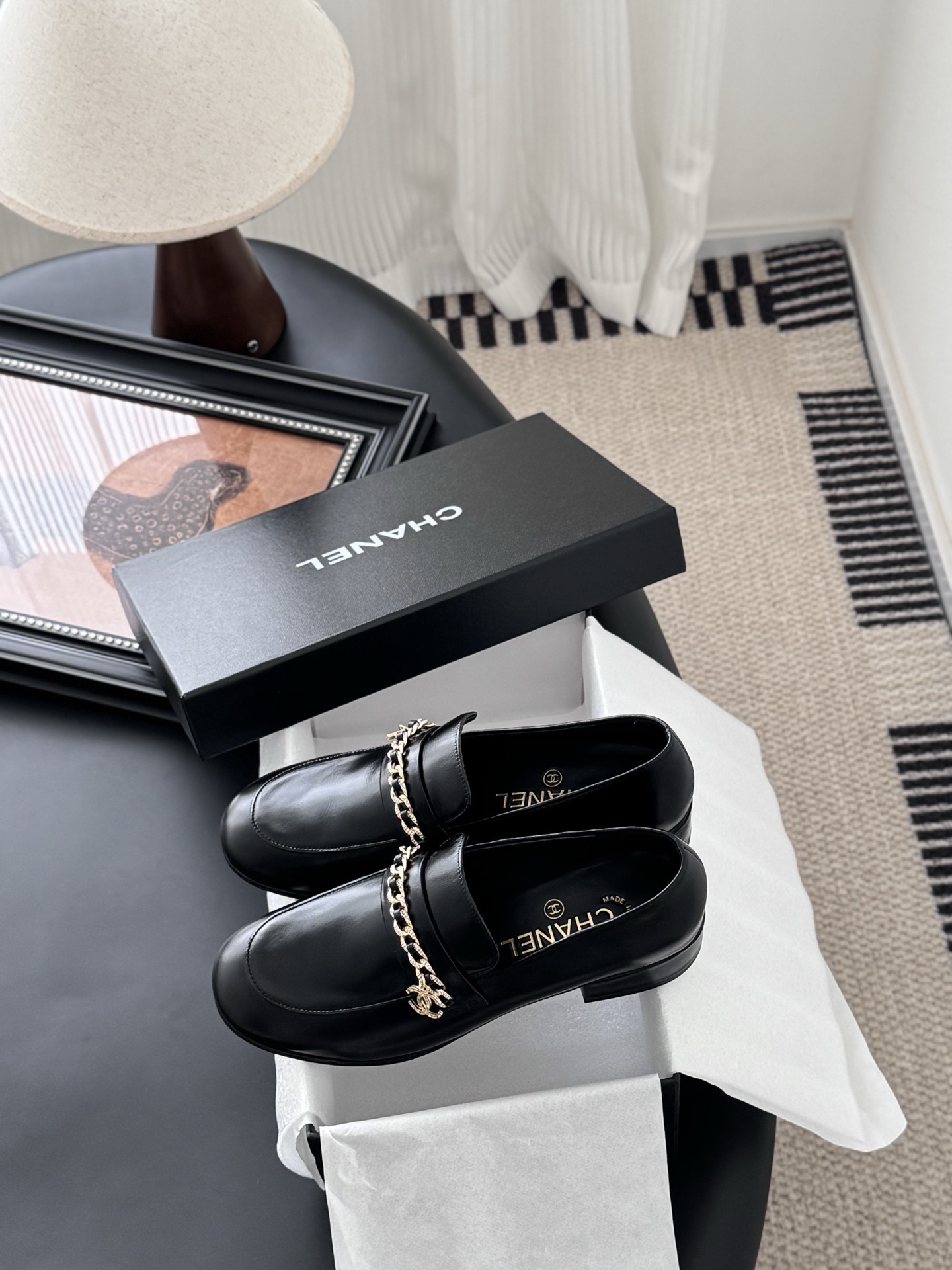 Pair of black Chanel leather loafers with gold chain and CC logo detail next to original box - Hình 9