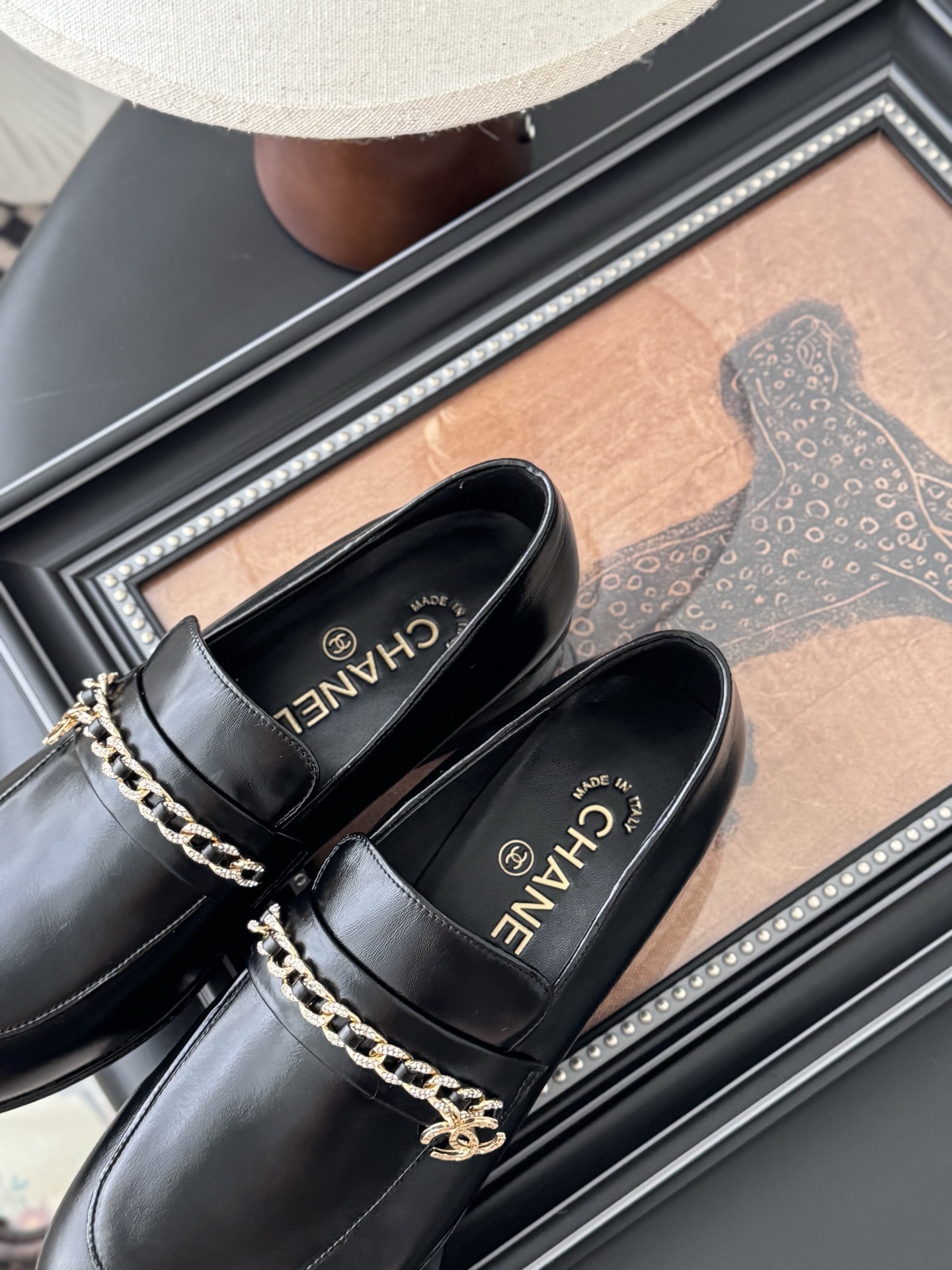 Pair of black Chanel leather loafers with gold chain and CC logo detail next to original box - Hình 8