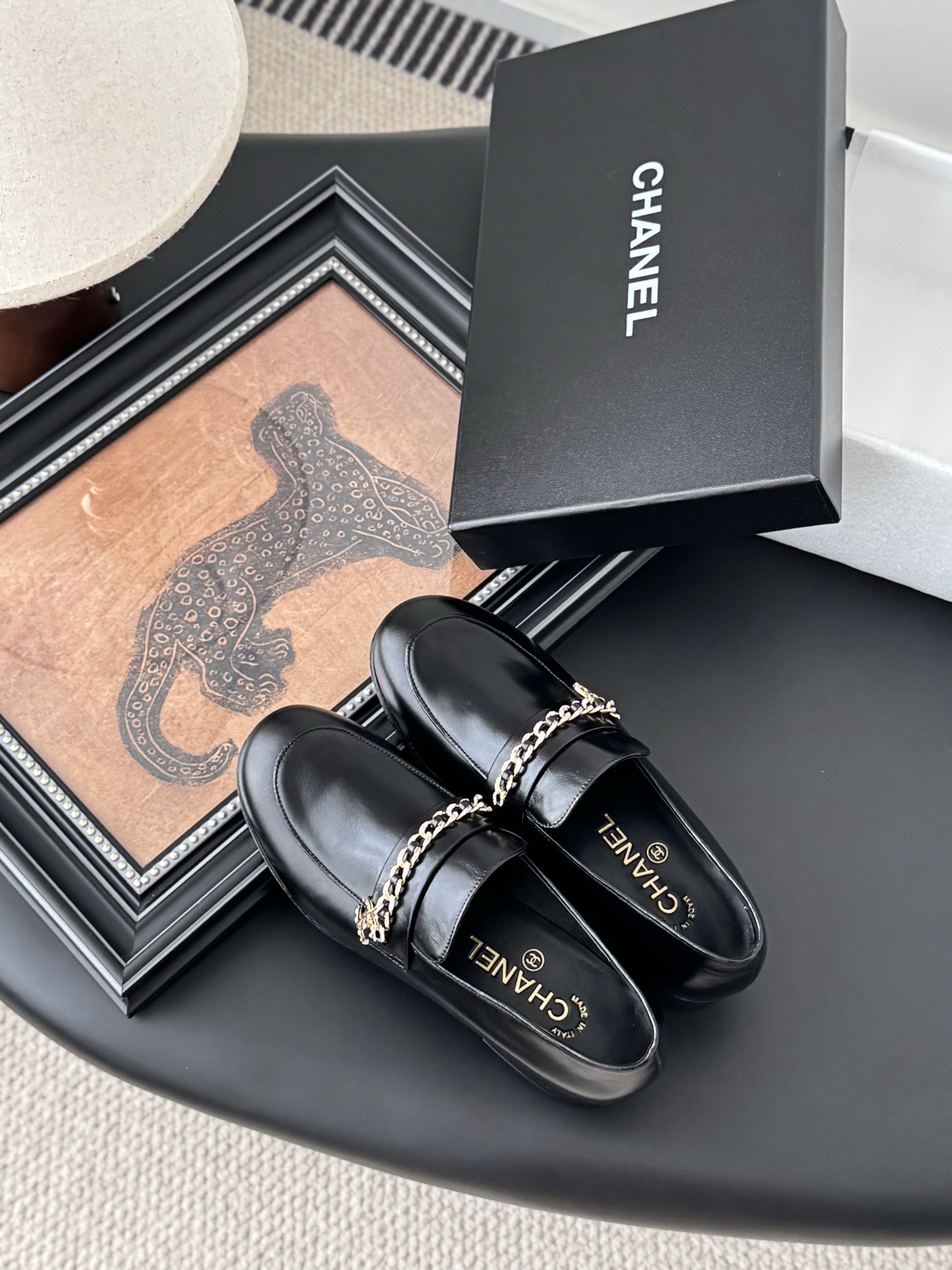 Pair of black Chanel leather loafers with gold chain and CC logo detail next to original box - Hình 7