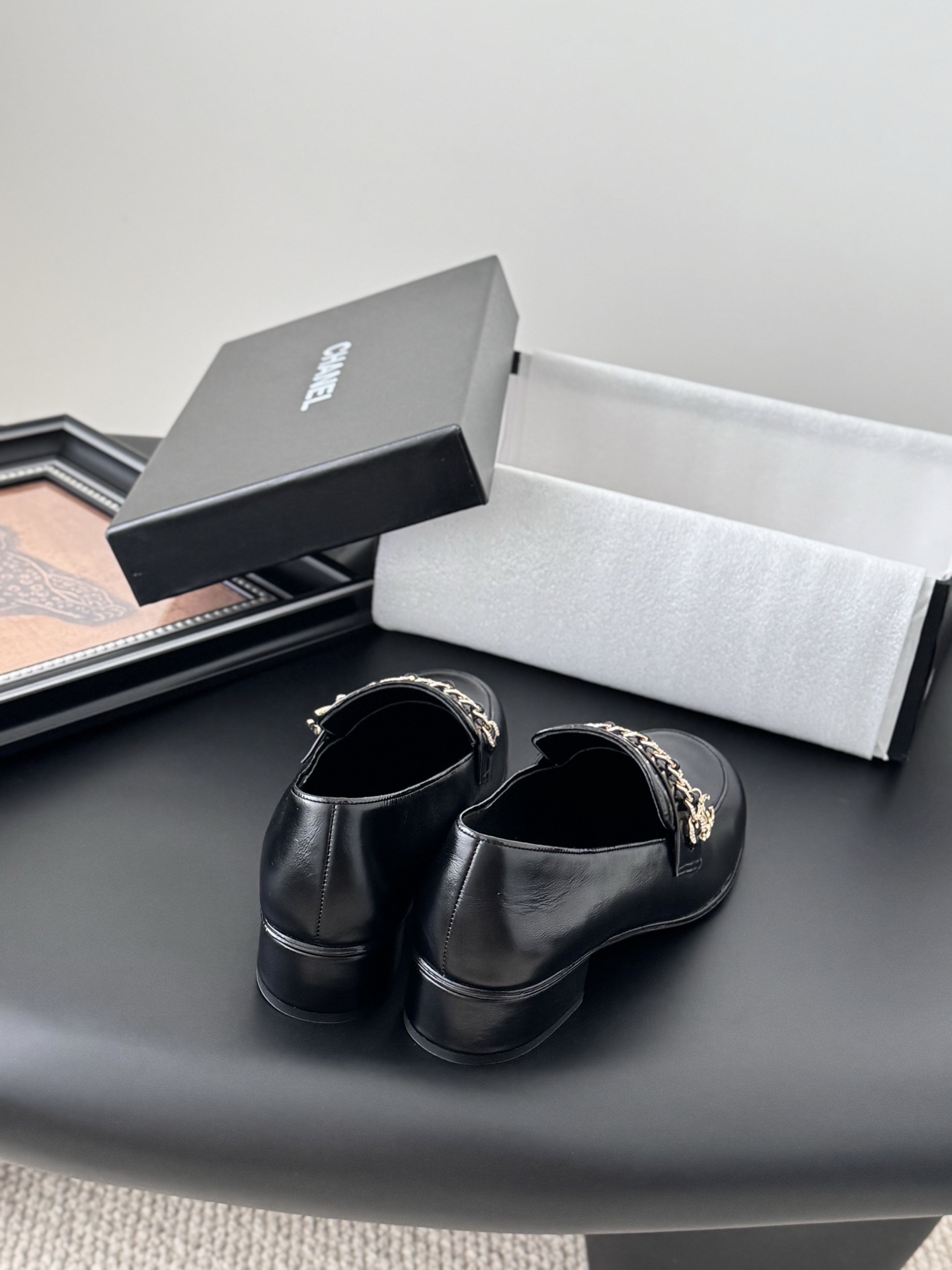 Pair of black Chanel leather loafers with gold chain and CC logo detail next to original box - Hình 6