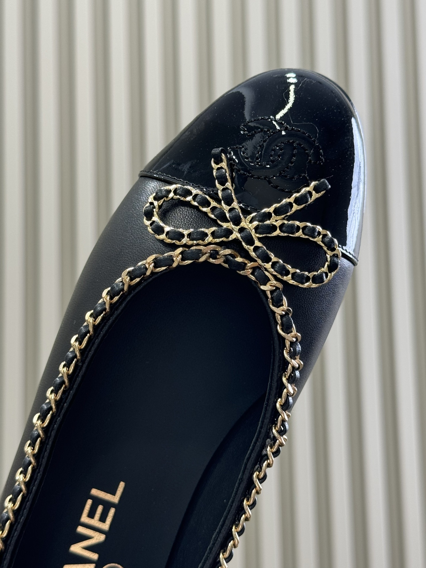 Pair of Chanel black leather ballet flats with patent cap toe and gold chain trim on a black box - Hình 4