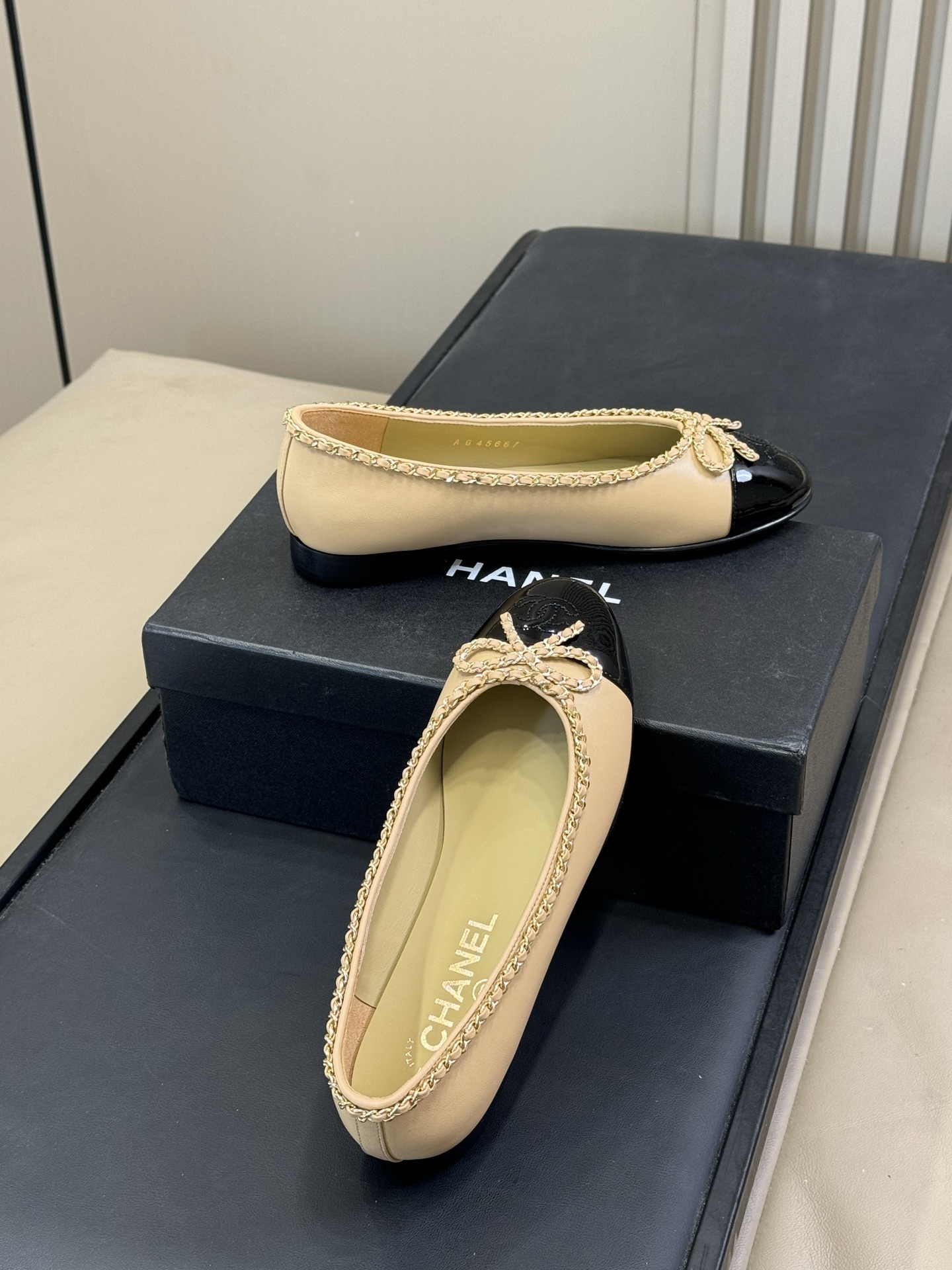 Pair of luxury beige leather ballet flats with black patent leather cap toes and gold chain link bow detailing - Hình 4