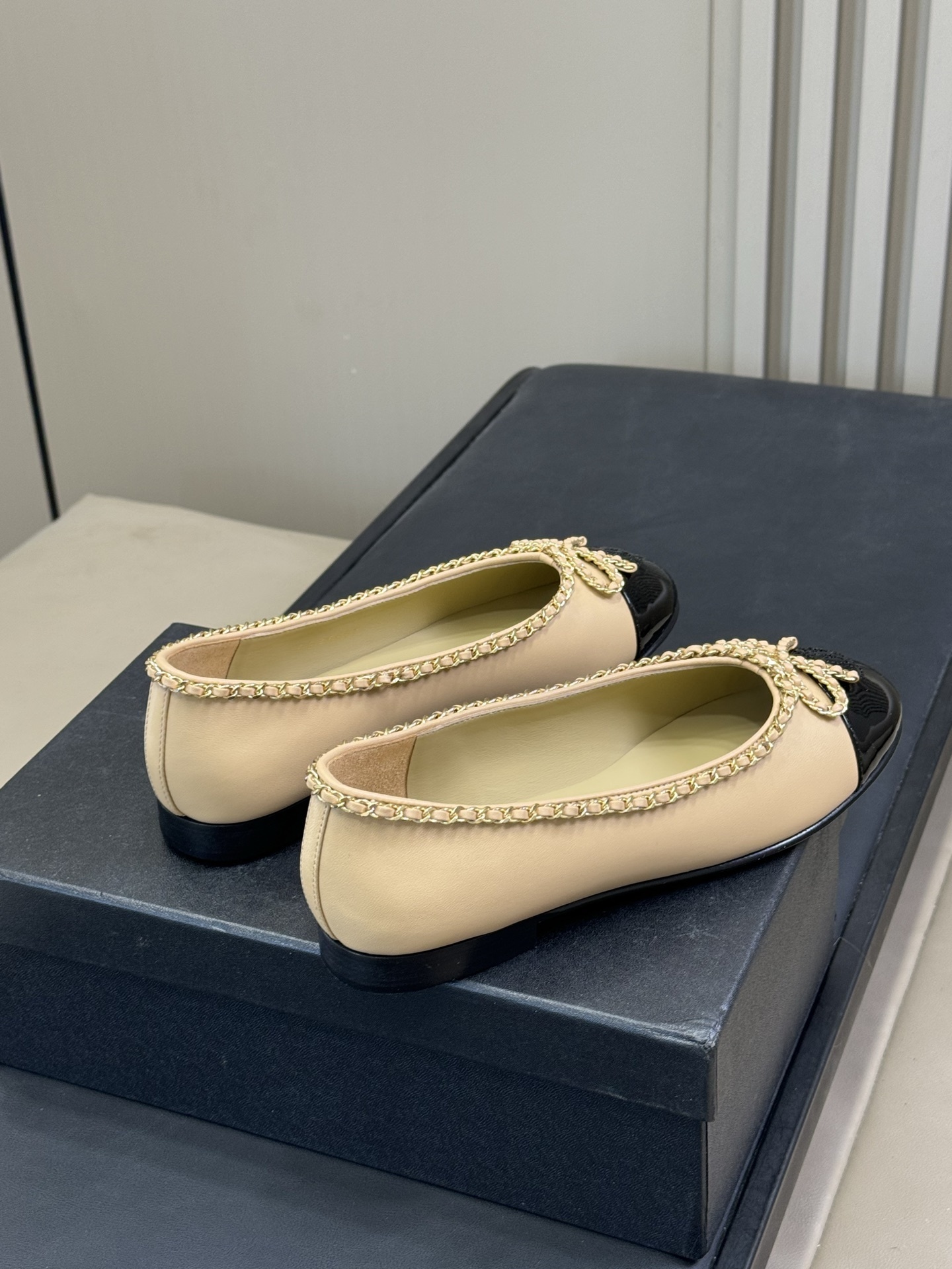 Pair of luxury beige leather ballet flats with black patent leather cap toes and gold chain link bow detailing - Hình 3