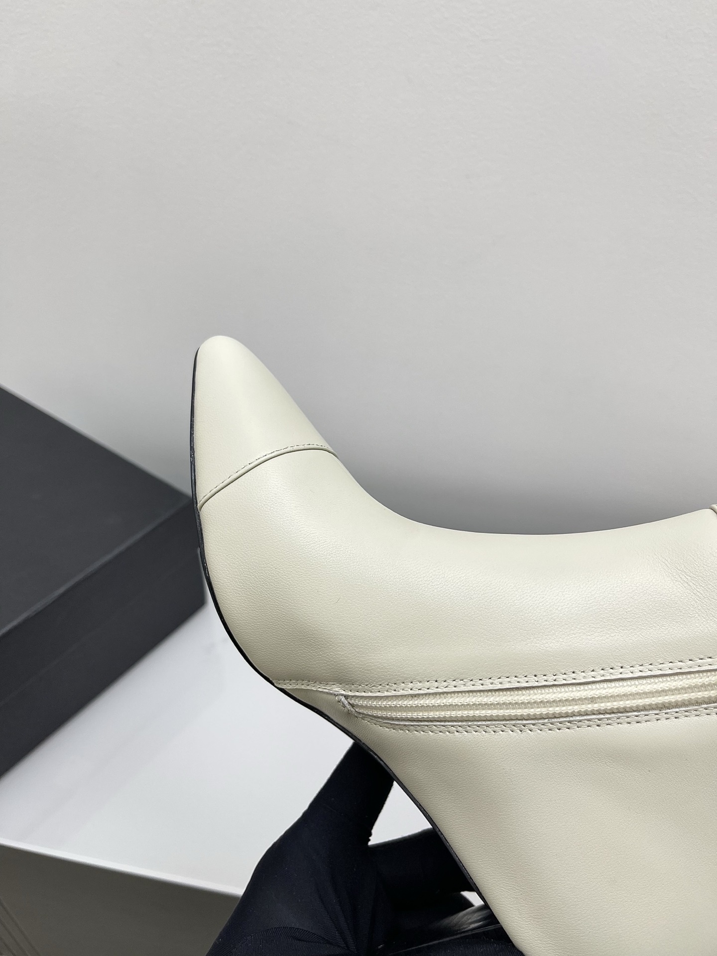 Pair of Chanel ivory leather pointed-toe ankle boots with gold lion head emblem and side zipper on a white marble surface. - Hình 6