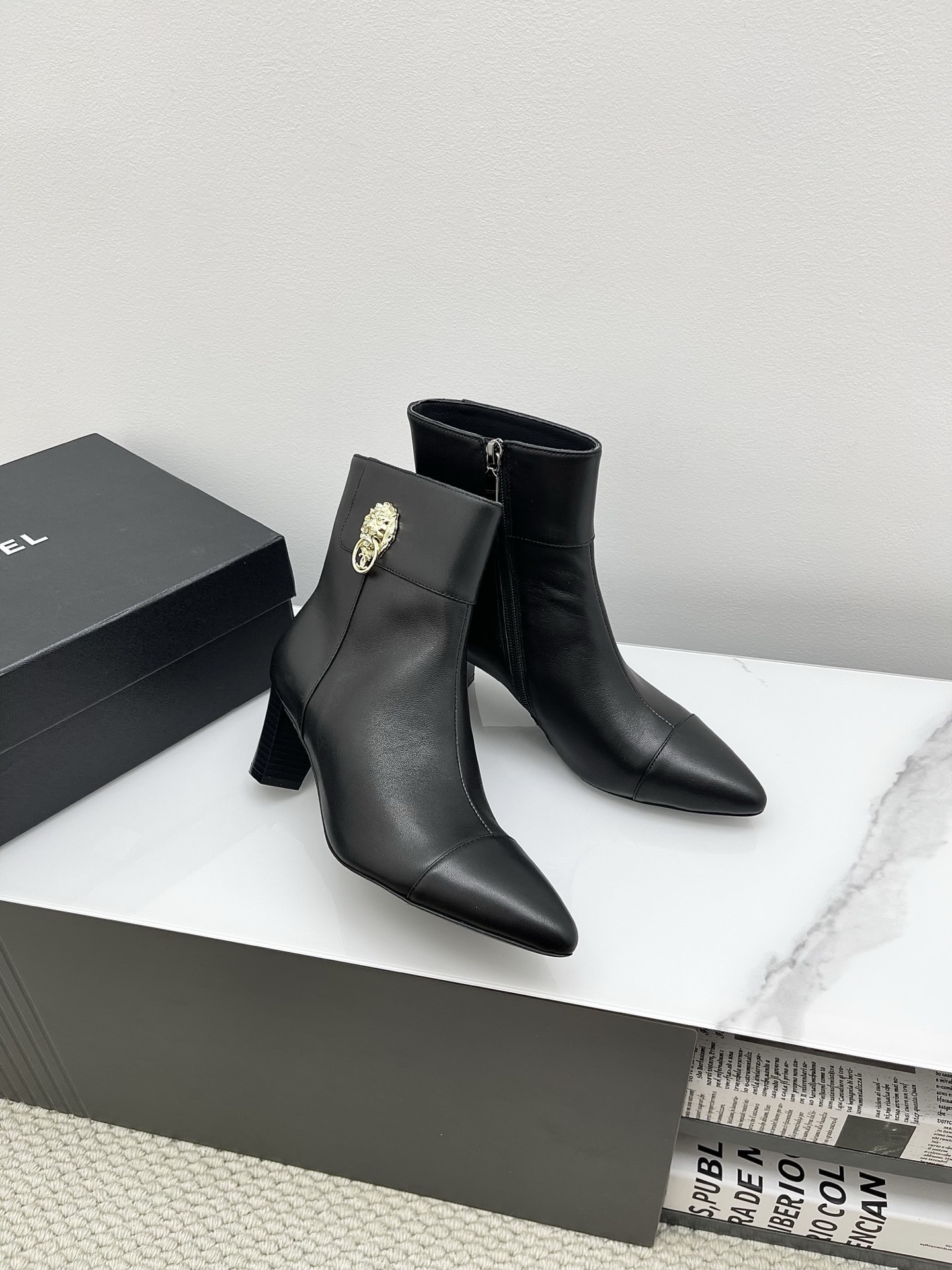 Chanel black leather pointed-toe ankle boots with side zippers and block heels shown next to a signature Chanel box. - Hình 9
