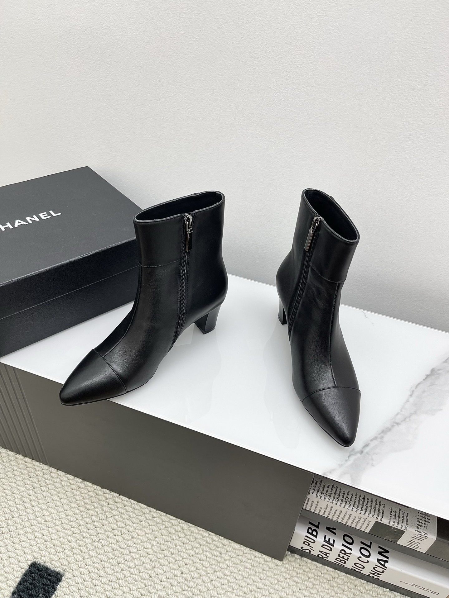 Chanel black leather pointed-toe ankle boots with side zippers and block heels shown next to a signature Chanel box. - Hình 8