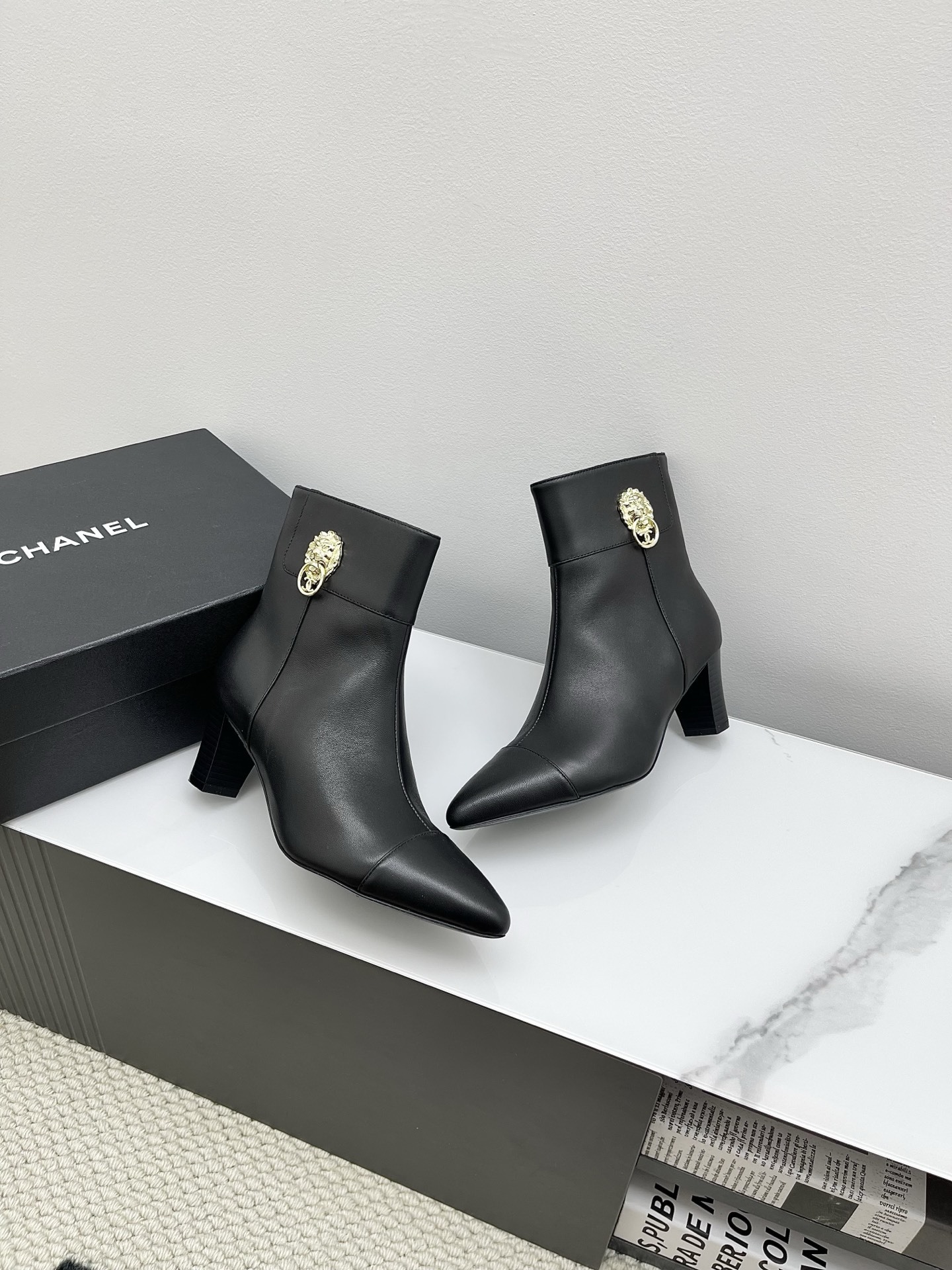 Chanel black leather pointed-toe ankle boots with side zippers and block heels shown next to a signature Chanel box. - Hình 5