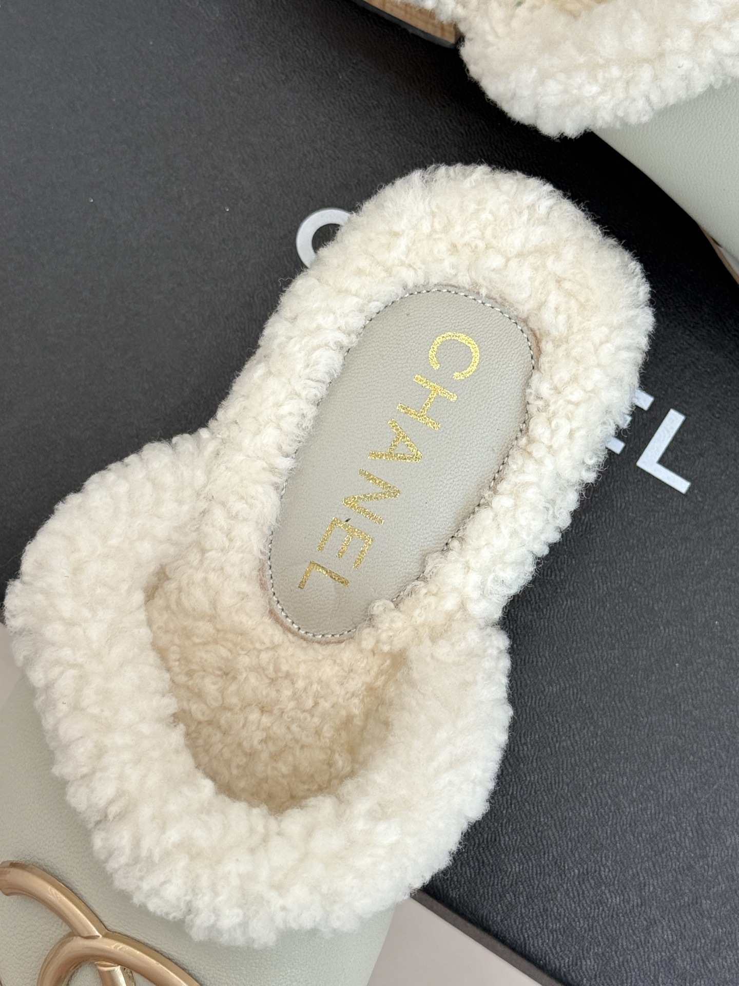 Pair of luxury off-white Chanel leather clogs with shearling lining and gold-tone CC logo displayed on a black box. - Hình 8