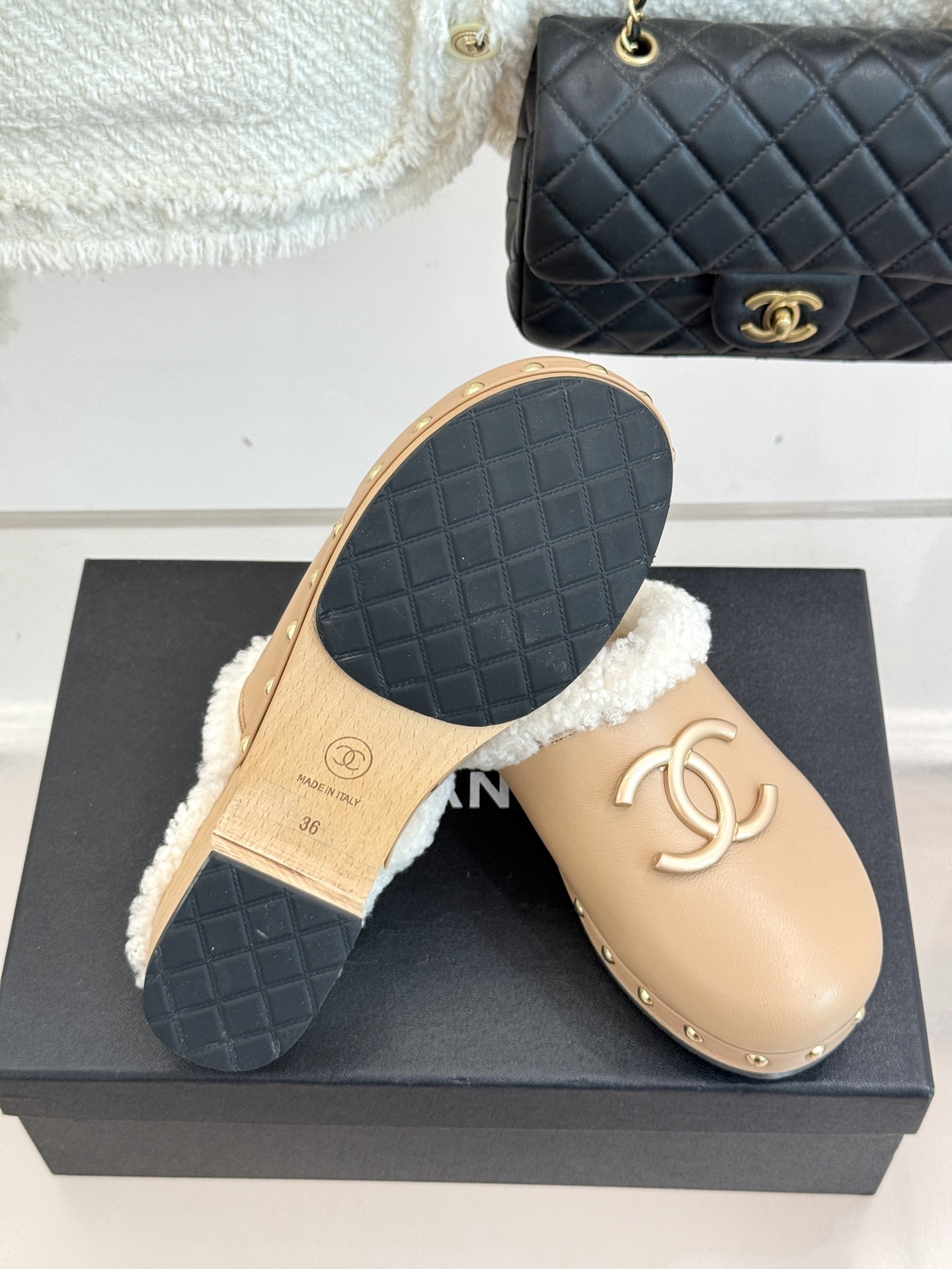Pair of luxury Chanel beige leather clogs with white shearling lining and gold CC logo displayed on a black box - Hình 9