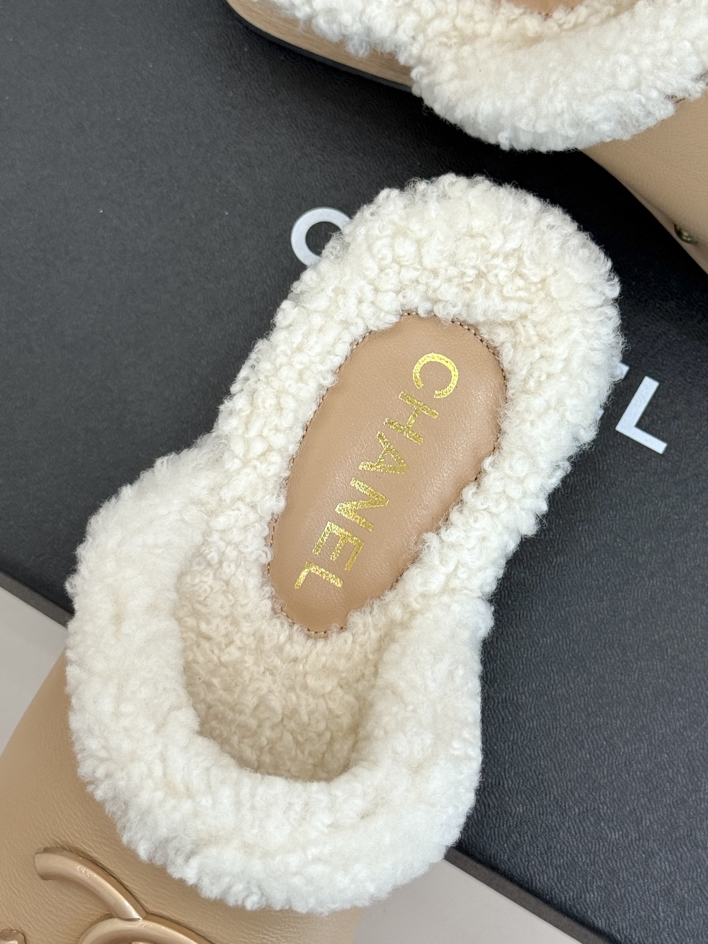Pair of luxury Chanel beige leather clogs with white shearling lining and gold CC logo displayed on a black box - Hình 8