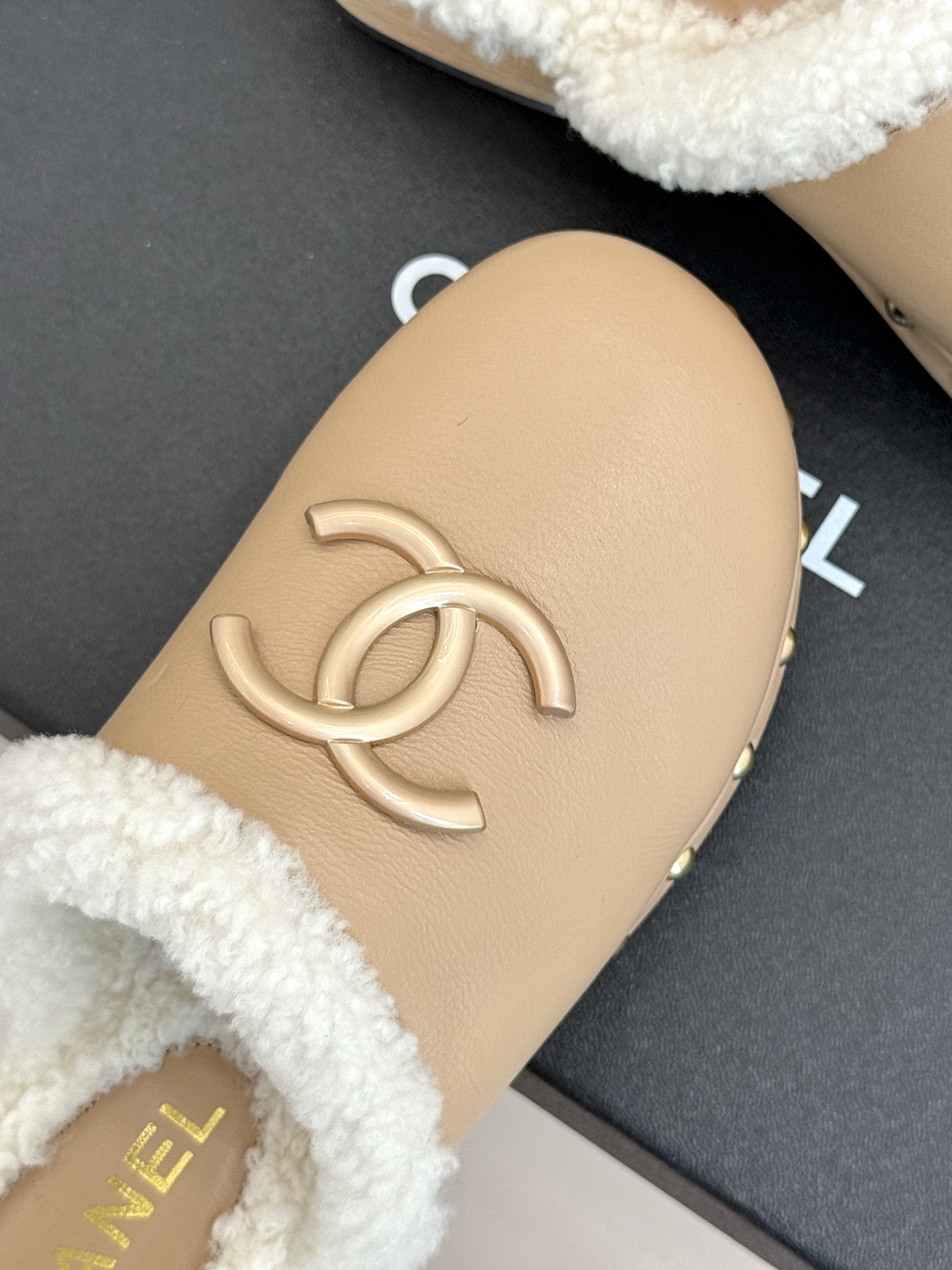 Pair of luxury Chanel beige leather clogs with white shearling lining and gold CC logo displayed on a black box - Hình 7