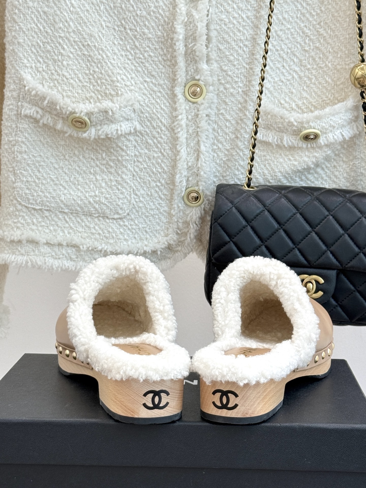 Pair of luxury Chanel beige leather clogs with white shearling lining and gold CC logo displayed on a black box - Hình 6