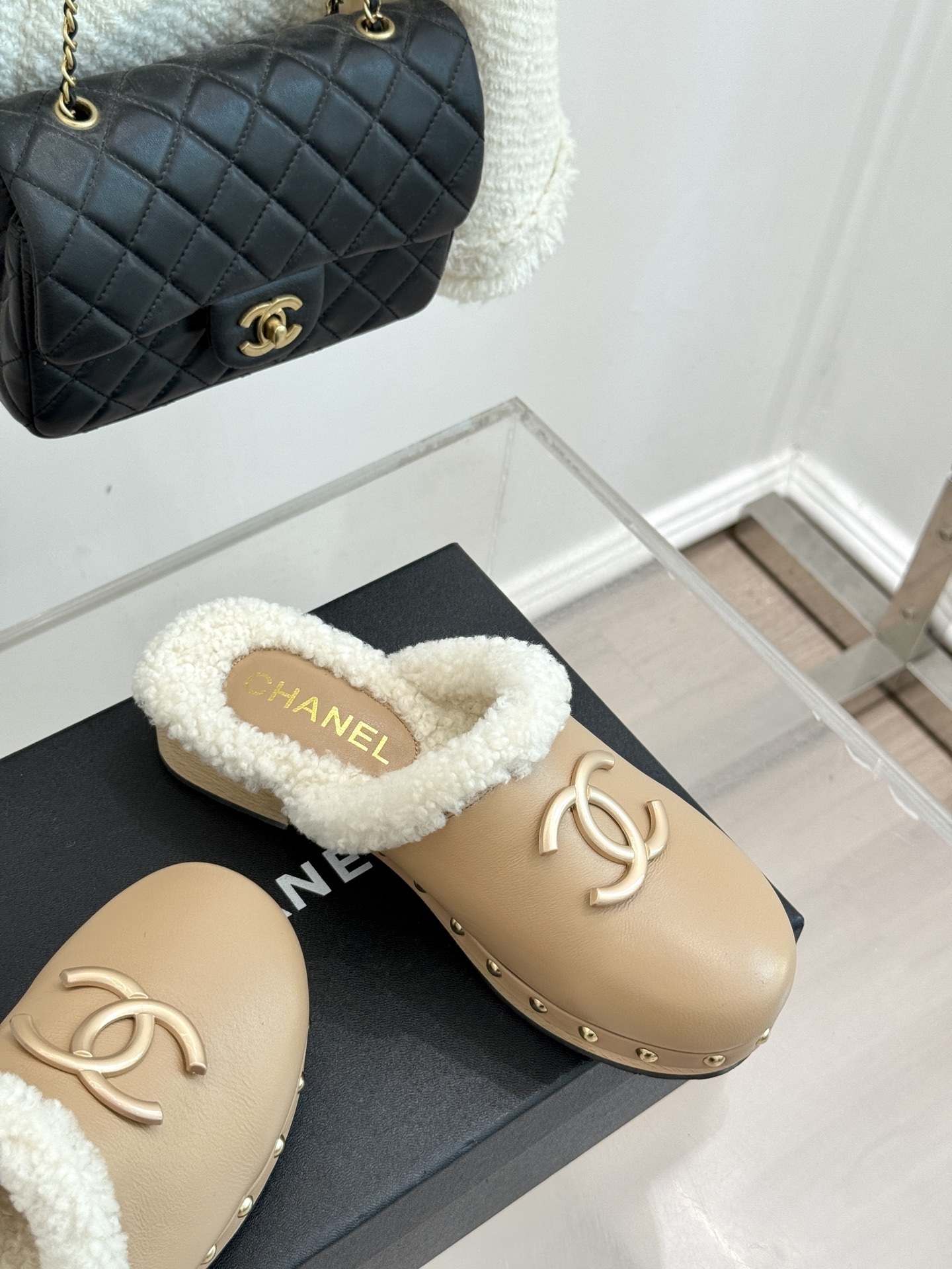 Pair of luxury Chanel beige leather clogs with white shearling lining and gold CC logo displayed on a black box - Hình 5