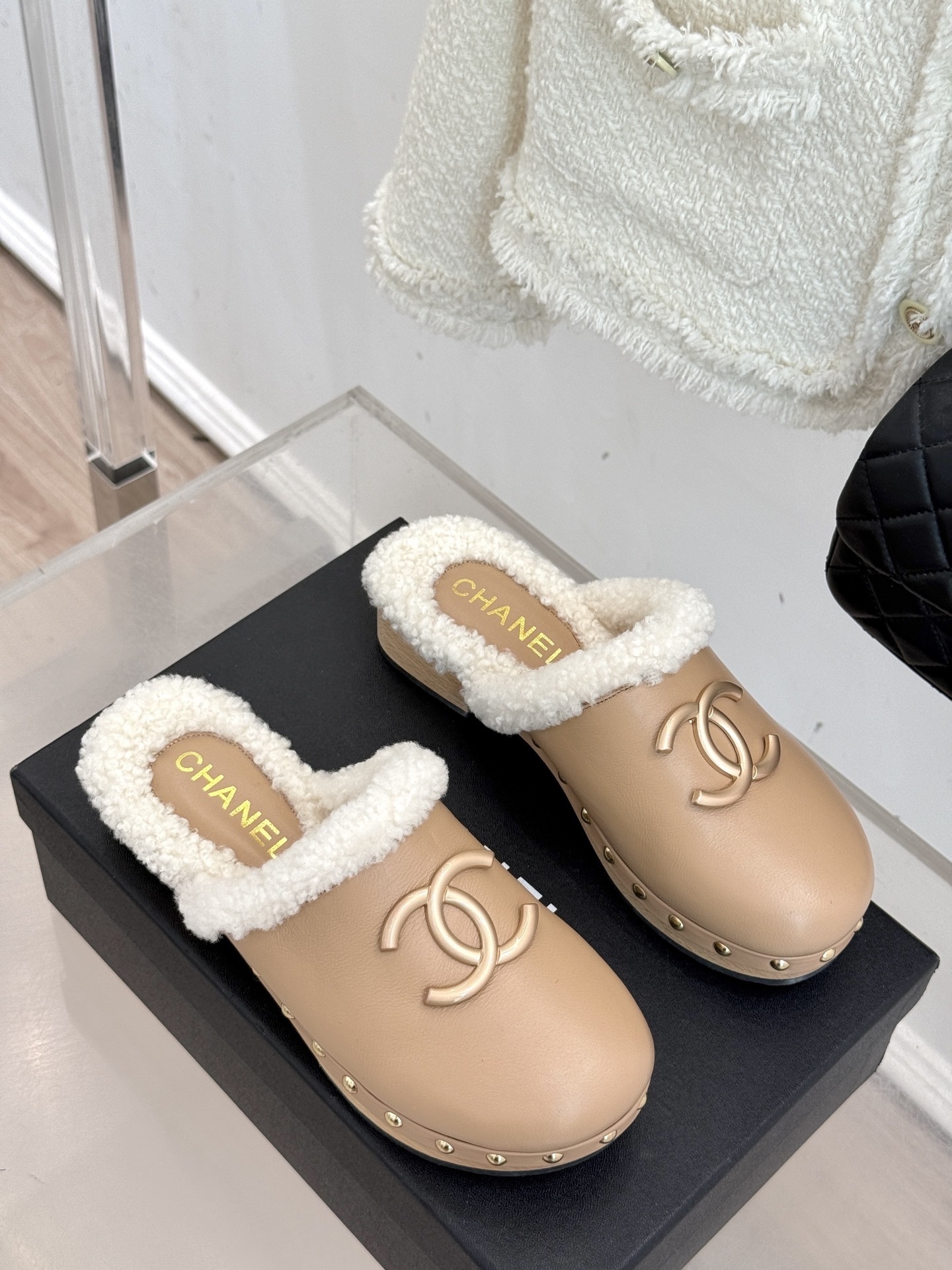 Pair of luxury Chanel beige leather clogs with white shearling lining and gold CC logo displayed on a black box - Hình 3